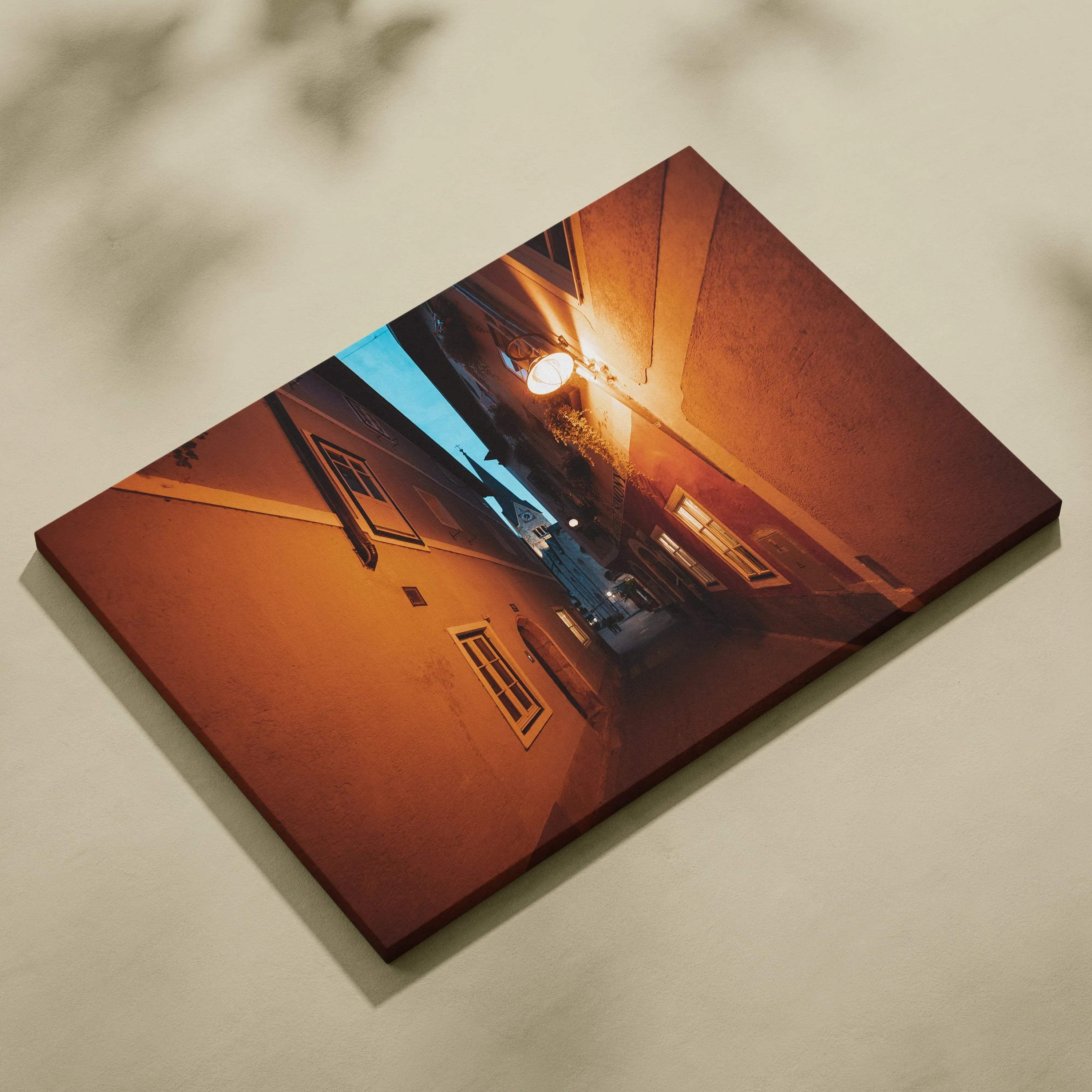 Warm-toned architectural canvas wall art featuring a narrow alley with illuminated lamps at dusk.