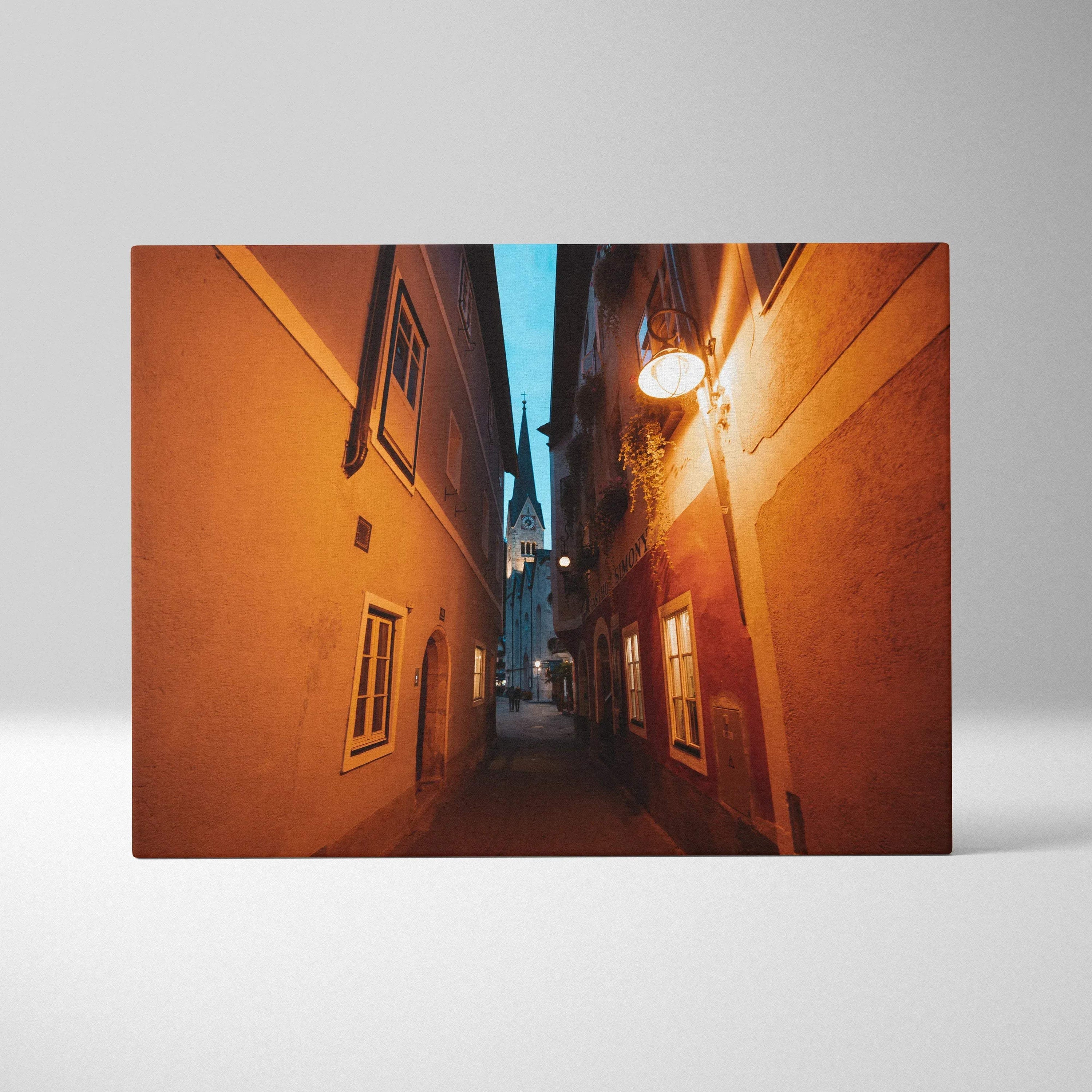 Canvas wall art featuring a narrow, warmly lit urban alleyway with textured buildings and glowing street lamps at dusk.