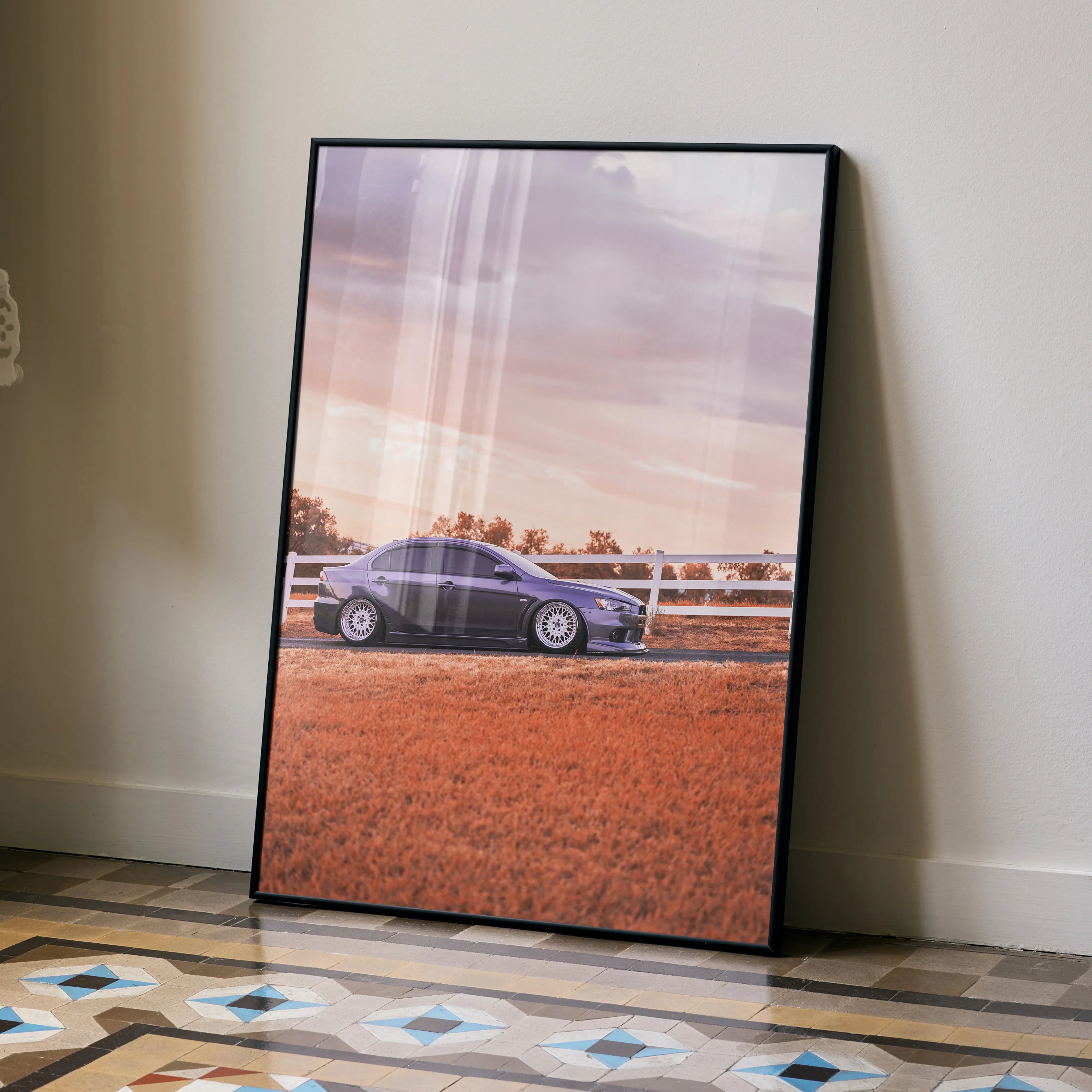 Mitsubishi Evo 10 poster wall art featuring car on rural road with sunset sky in black frame.