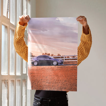 Poster of black Mitsubishi Evo 10 parked on reddish dirt with a pink and purple sky wall art.