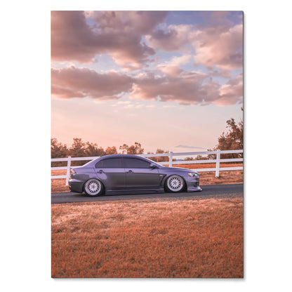 Mitsubishi Evo 10 poster showing sleek gray car parked by white fence under colorful sunset sky wall art.