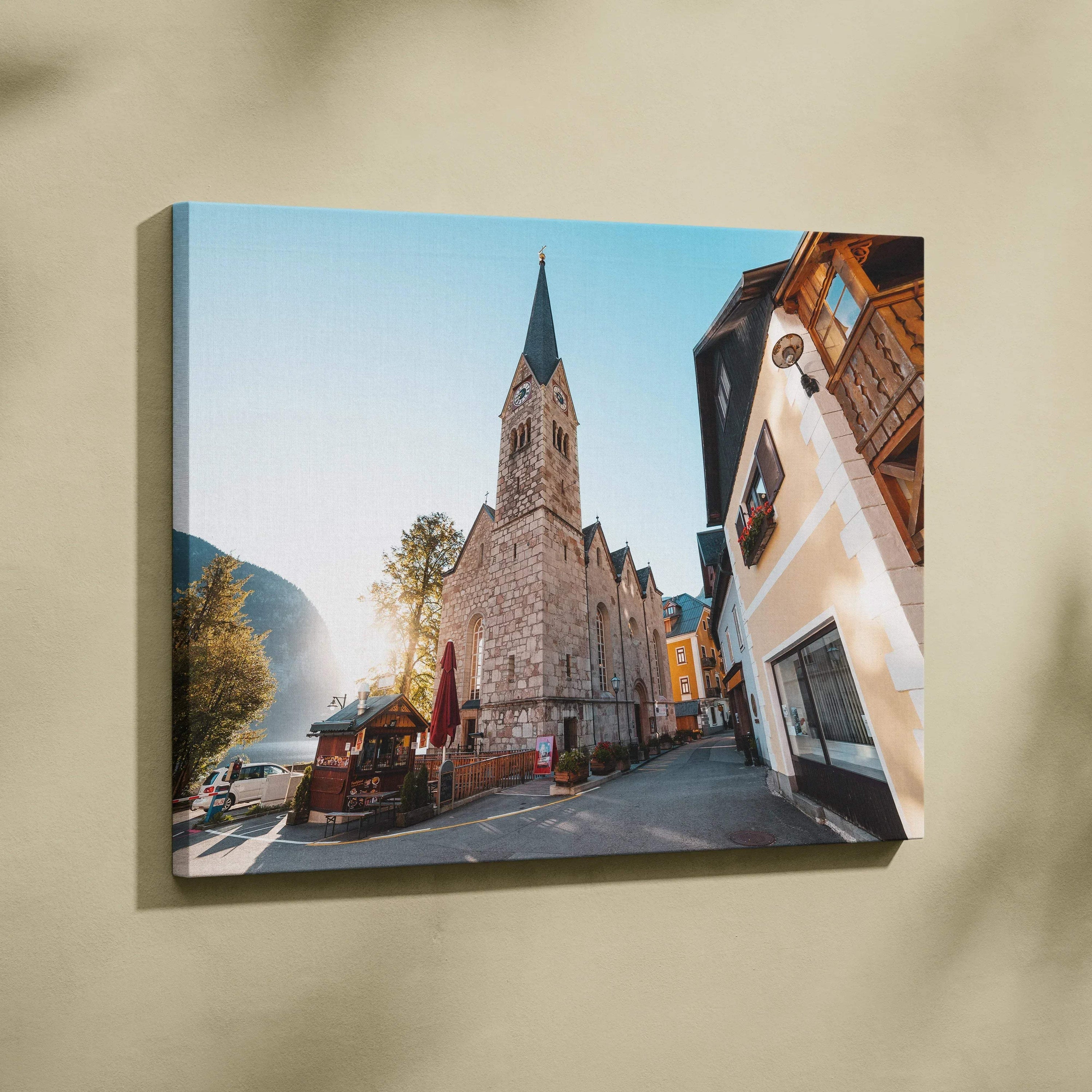 Canvas wall art featuring a tall stone church with a pointed steeple set against a clear blue sky in a quaint town scene.