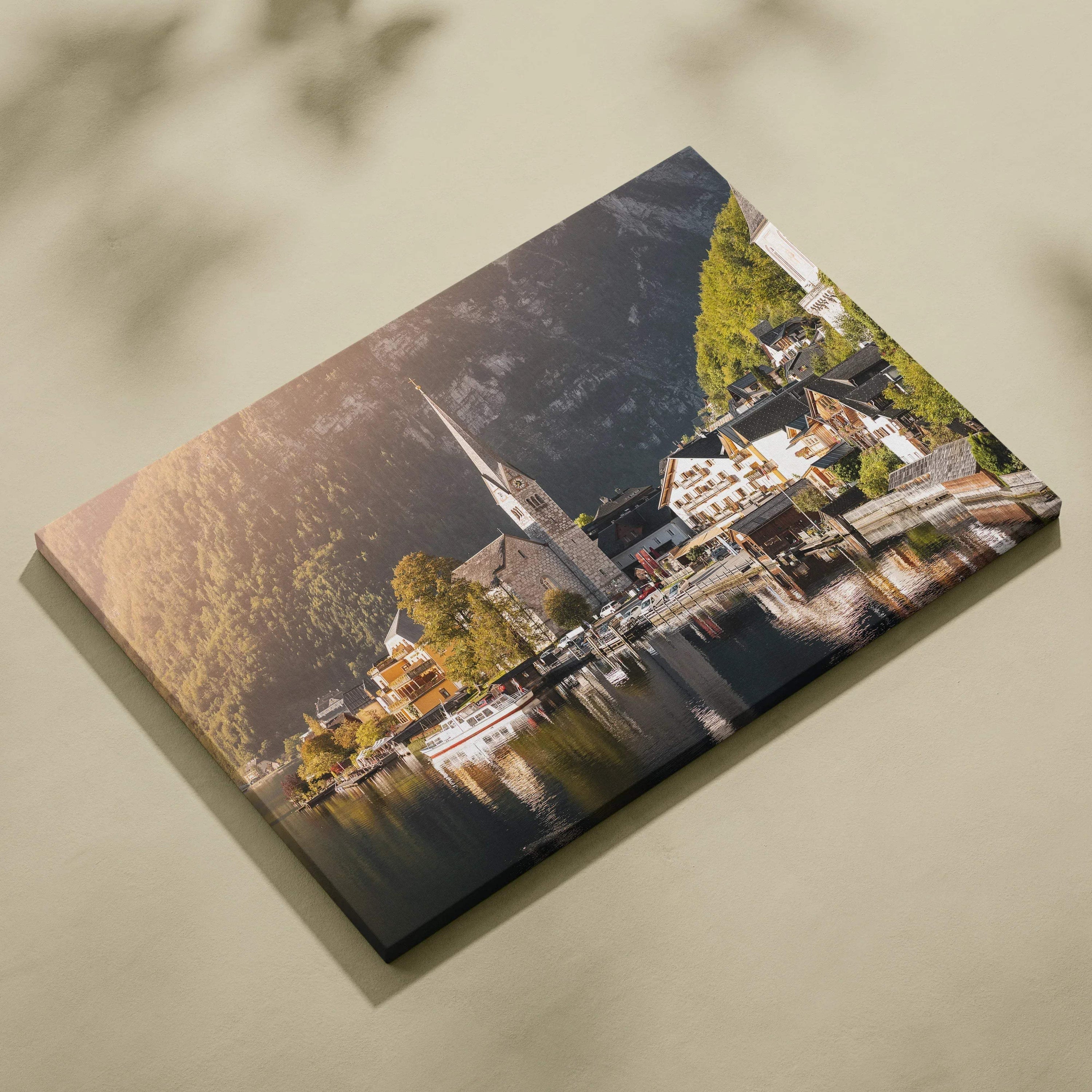 Canvas wall art print featuring a serene lakeside village with a church steeple, surrounded by forested hills at sunset.
