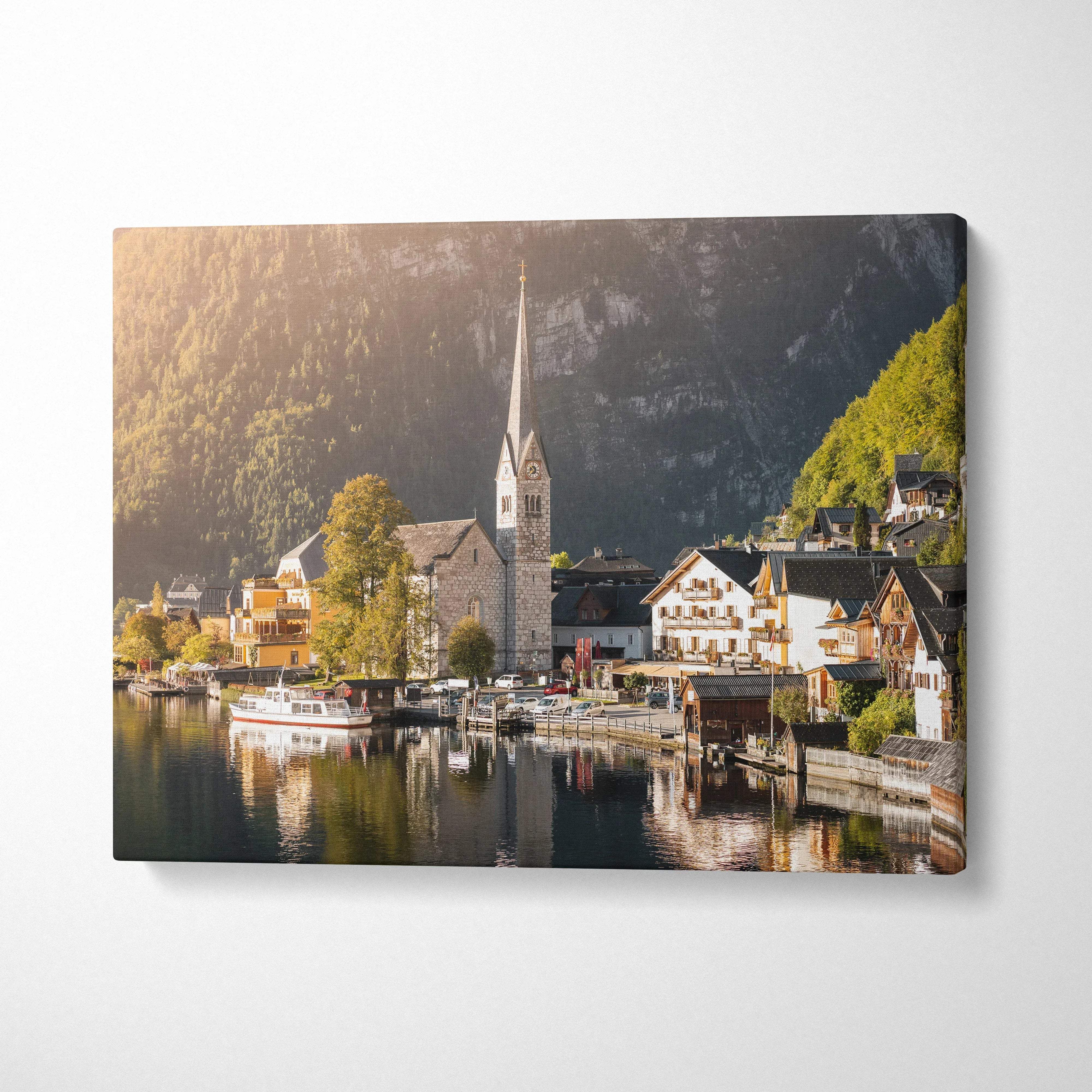 Canvas wall art featuring a serene lakeside village with a church and boats, vibrant natural lighting.