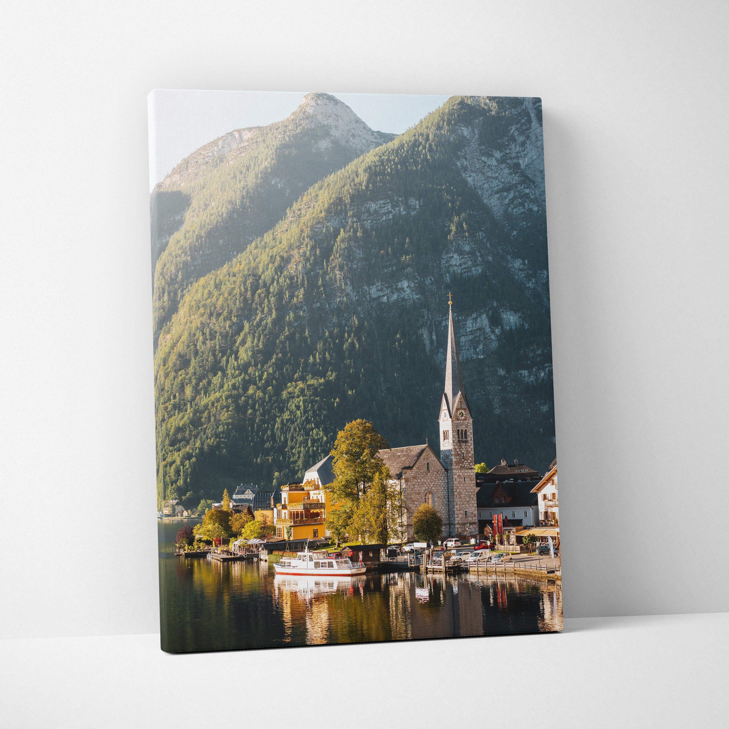 Canvas wall art featuring a scenic lakeside village with a tall church steeple and green mountain backdrop.