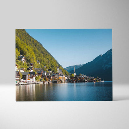 Canvas wall art depicting a serene lakeside village with colorful buildings and mountains under a clear blue sky.