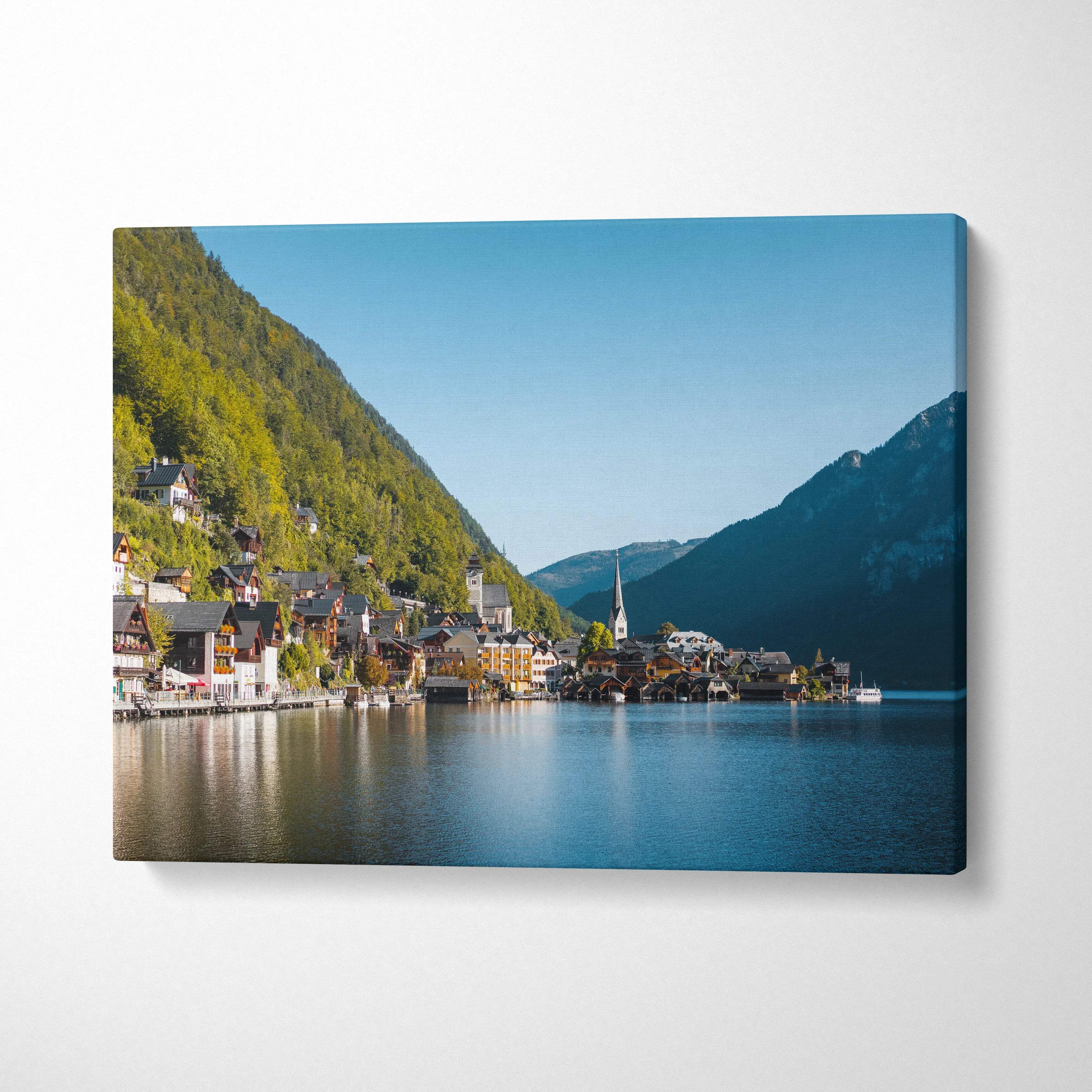 Canvas wall art featuring a serene lakeside village with mountains under a clear blue sky.