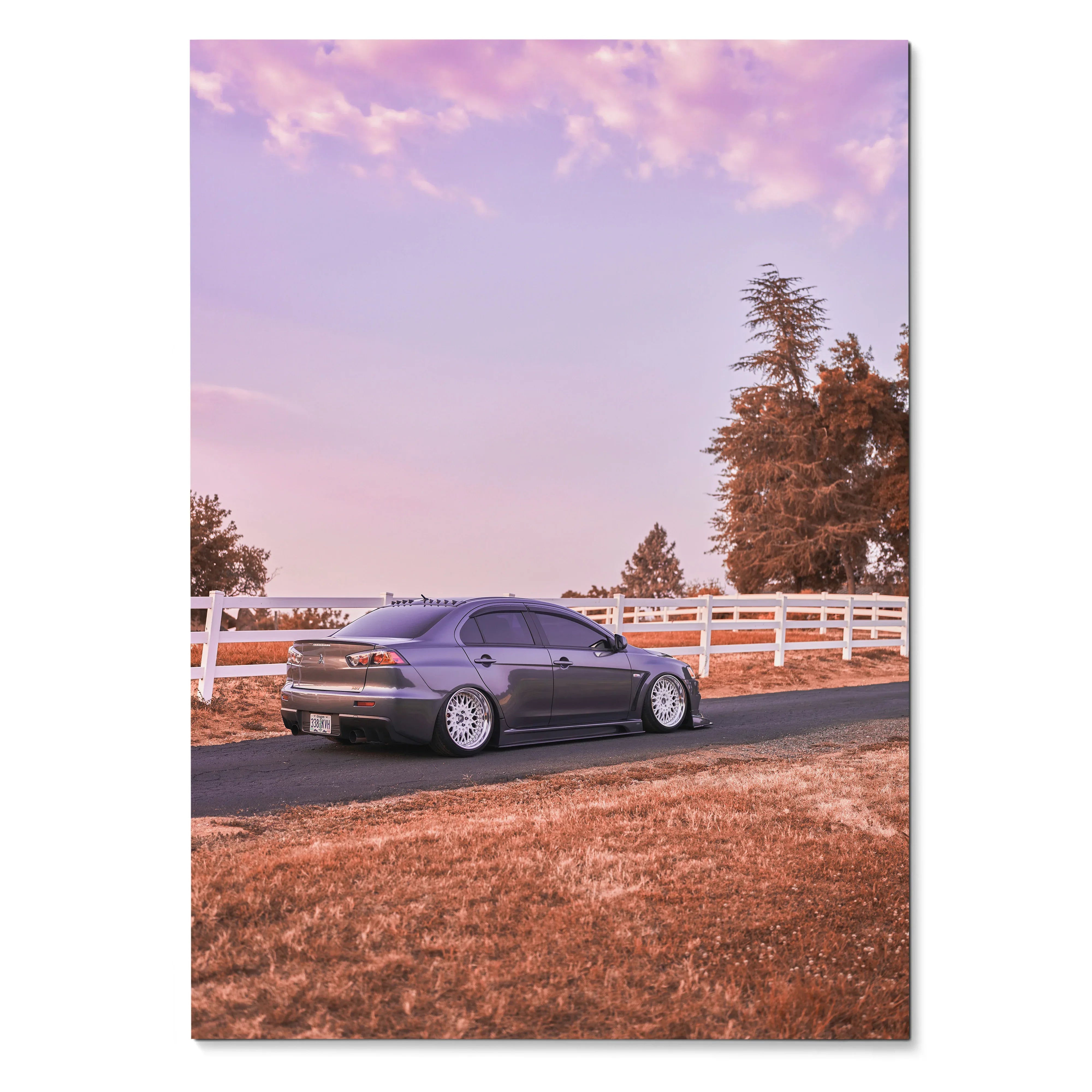Mitsubishi Evo 10 sports car parked by white fence under pink sky wall art poster.