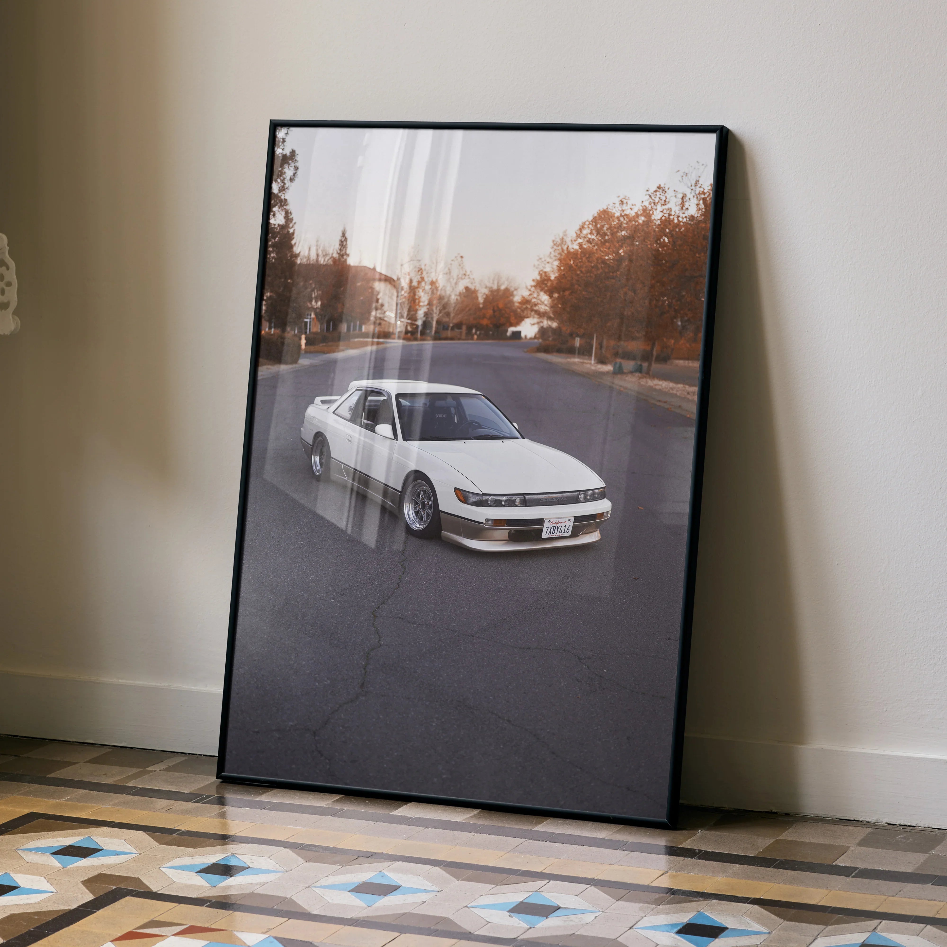 Nissan 240sx S13 Silvia driving on road autumn scene poster wall art in black frame.