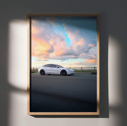 Tesla Model 3 Highland parked under vibrant sunset sky poster wall art in wooden frame.