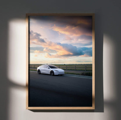 Tesla Model 3 Highland poster wall art featuring white car under dramatic sunset sky in wooden frame.