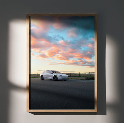 Tesla Model 3 Highland against a vibrant sunset sky poster wall art in wooden frame.
