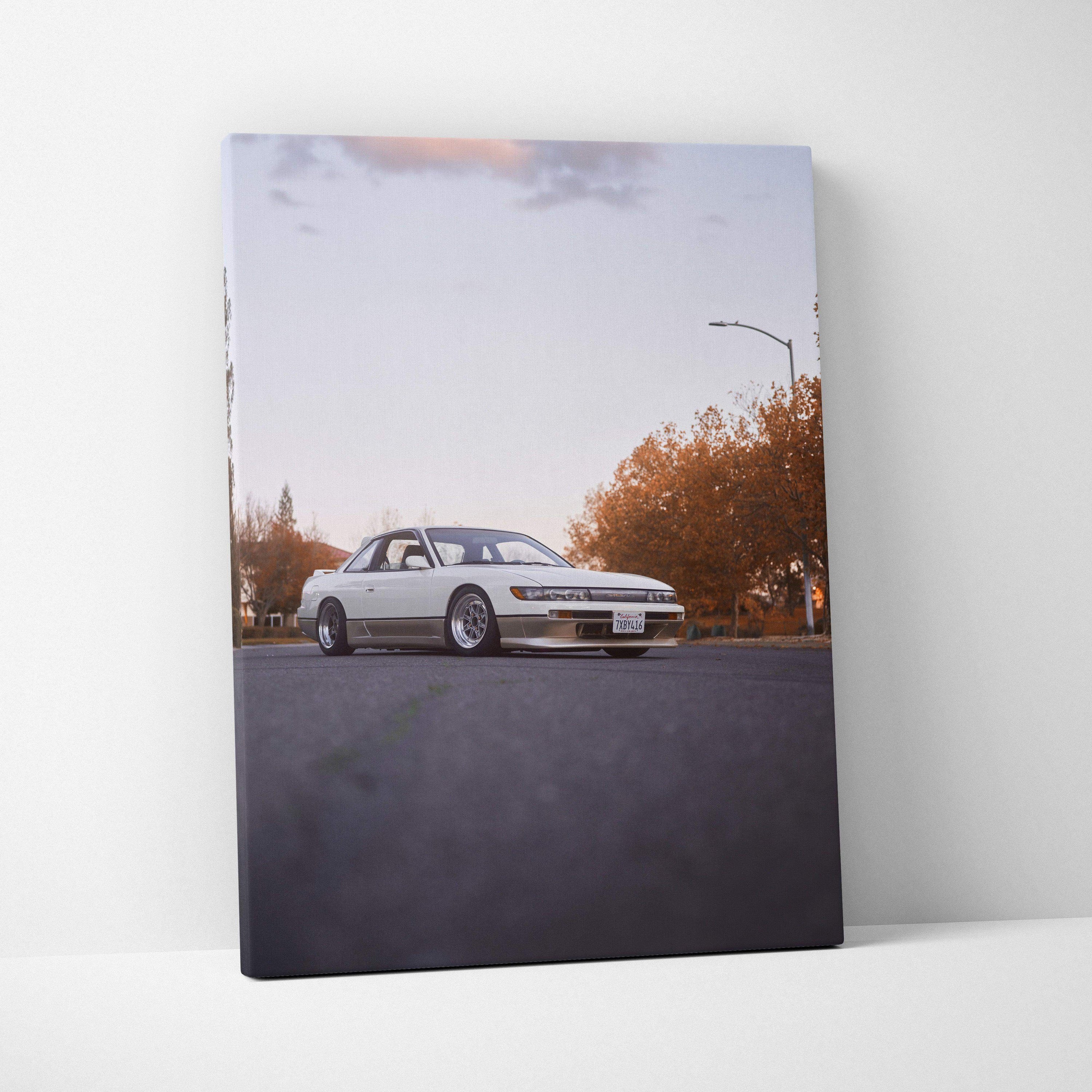 Vertical canvas wall art featuring a white Nissan 240sx S13 Silvia on a quiet street at sunset.