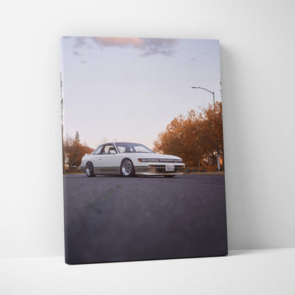 Vertical canvas wall art featuring a white Nissan 240sx S13 Silvia on a quiet street at sunset.