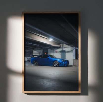 Nissan R34 GTR parked in a dimly lit garage poster wall art with wooden frame.