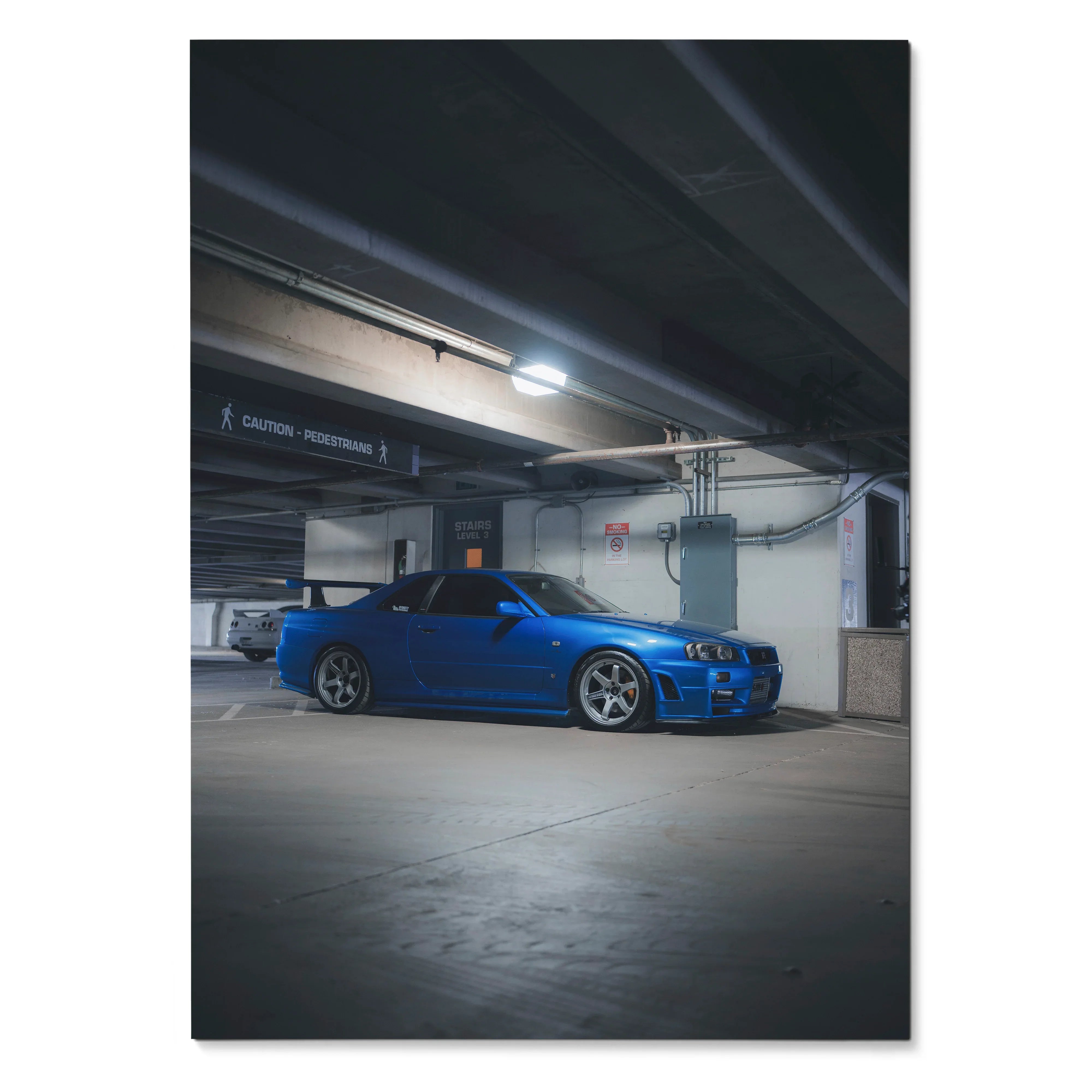 Blue Nissan R34 GTR Skyline parked in a dimly lit concrete garage poster wall art.