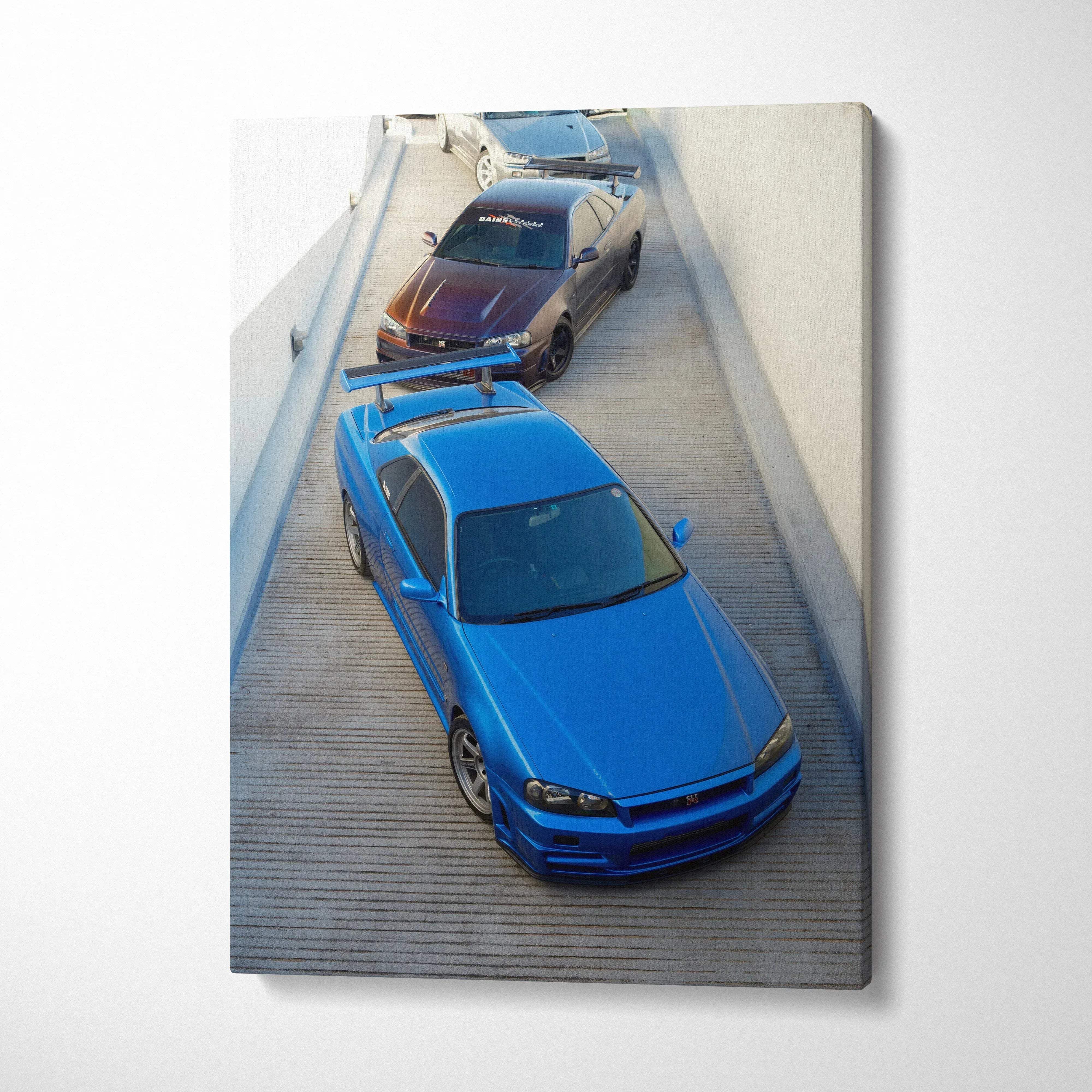 Vertical canvas art featuring blue and black Nissan R34 GTR cars parked on wood deck wall art.