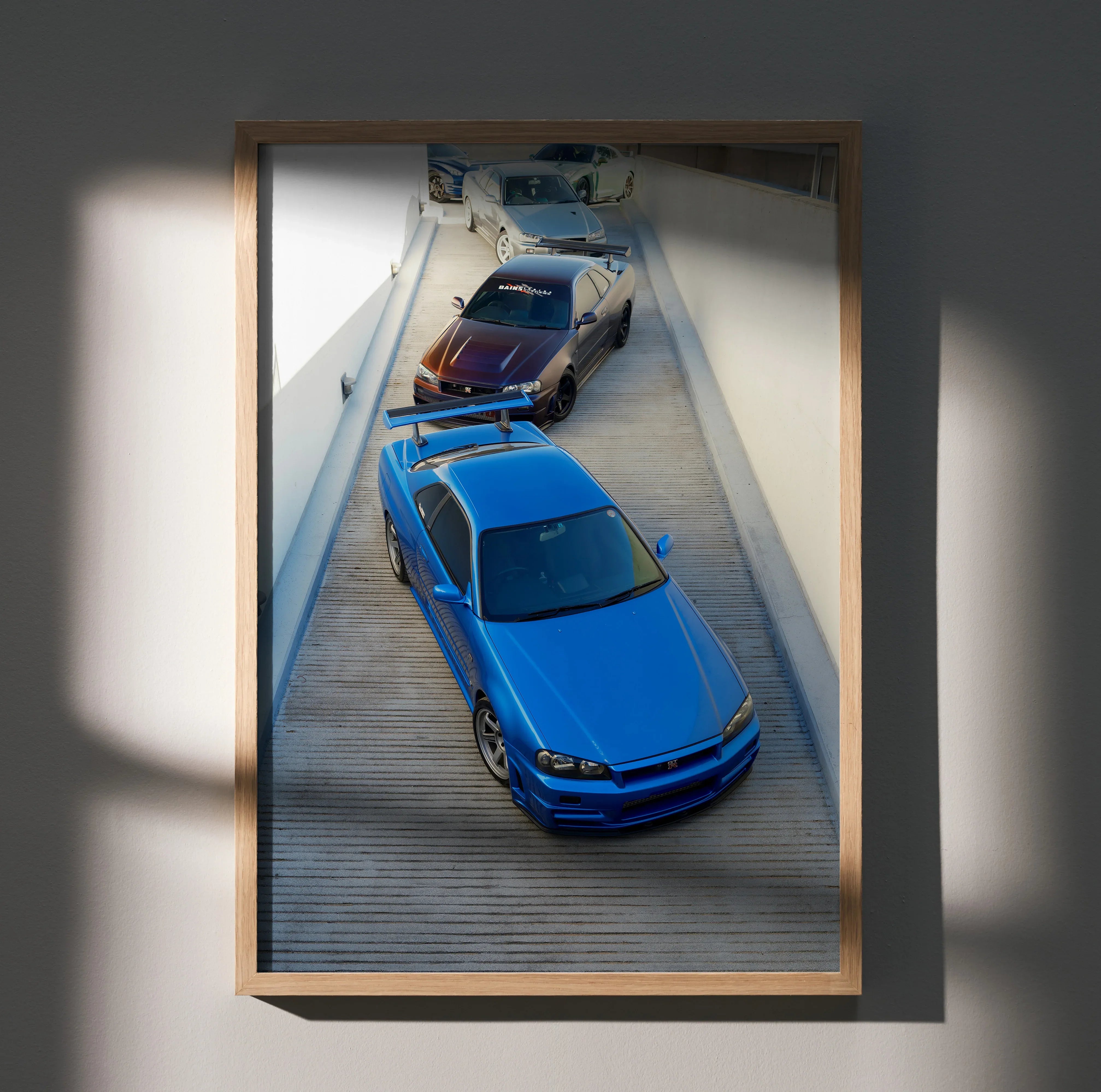 Poster of blue Nissan R34 GTR Skyline with red and white cars in alleyway wall art.