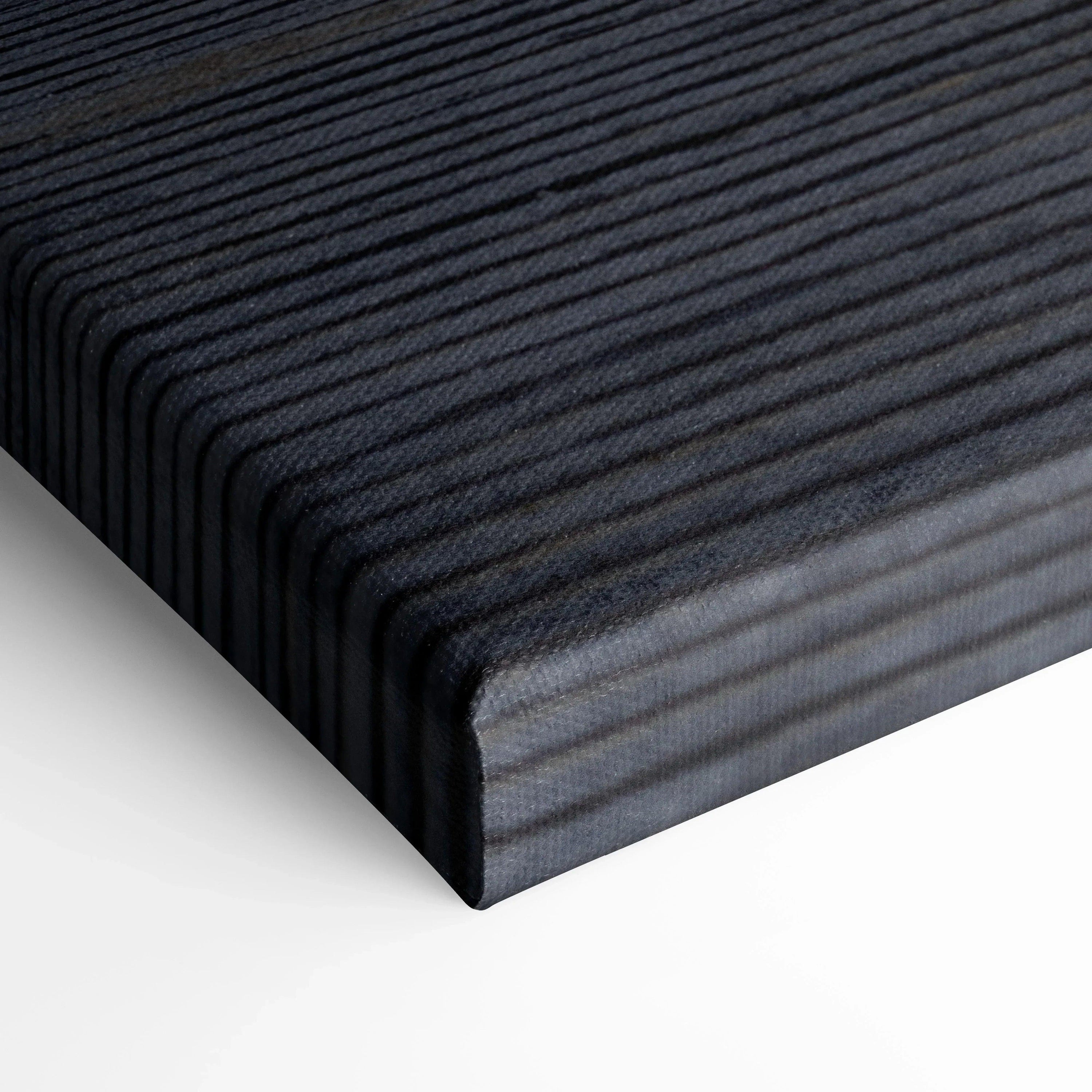 Close-up of black textured canvas wall art edge with fine horizontal ribbed pattern on thick stretcher bar.