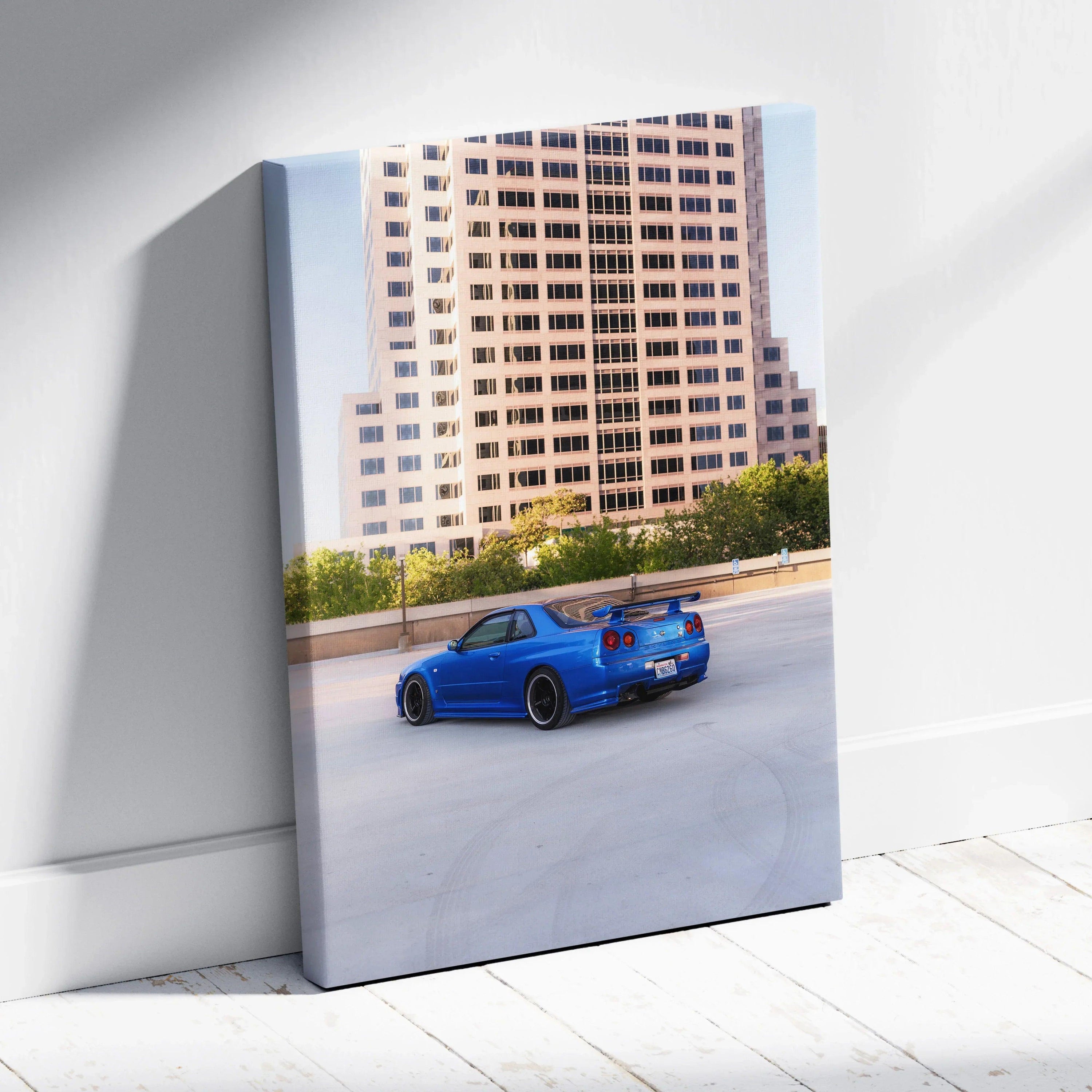 Vertical canvas art featuring a blue Nissan R34 GTR parked by urban high-rise buildings, wall art for car enthusiasts.
