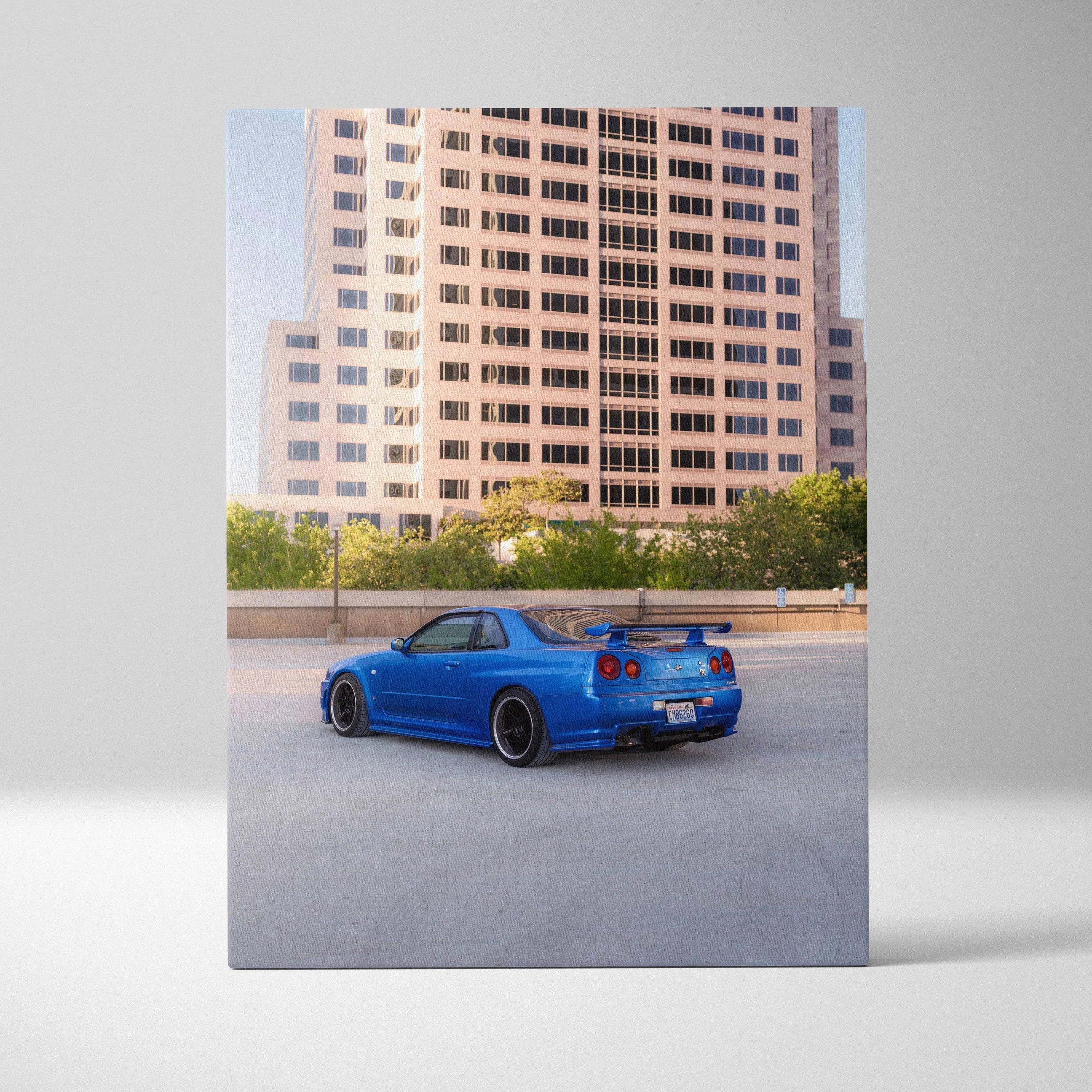 Blue Nissan R34 GTR parked in front of city building, vertical canvas art print.