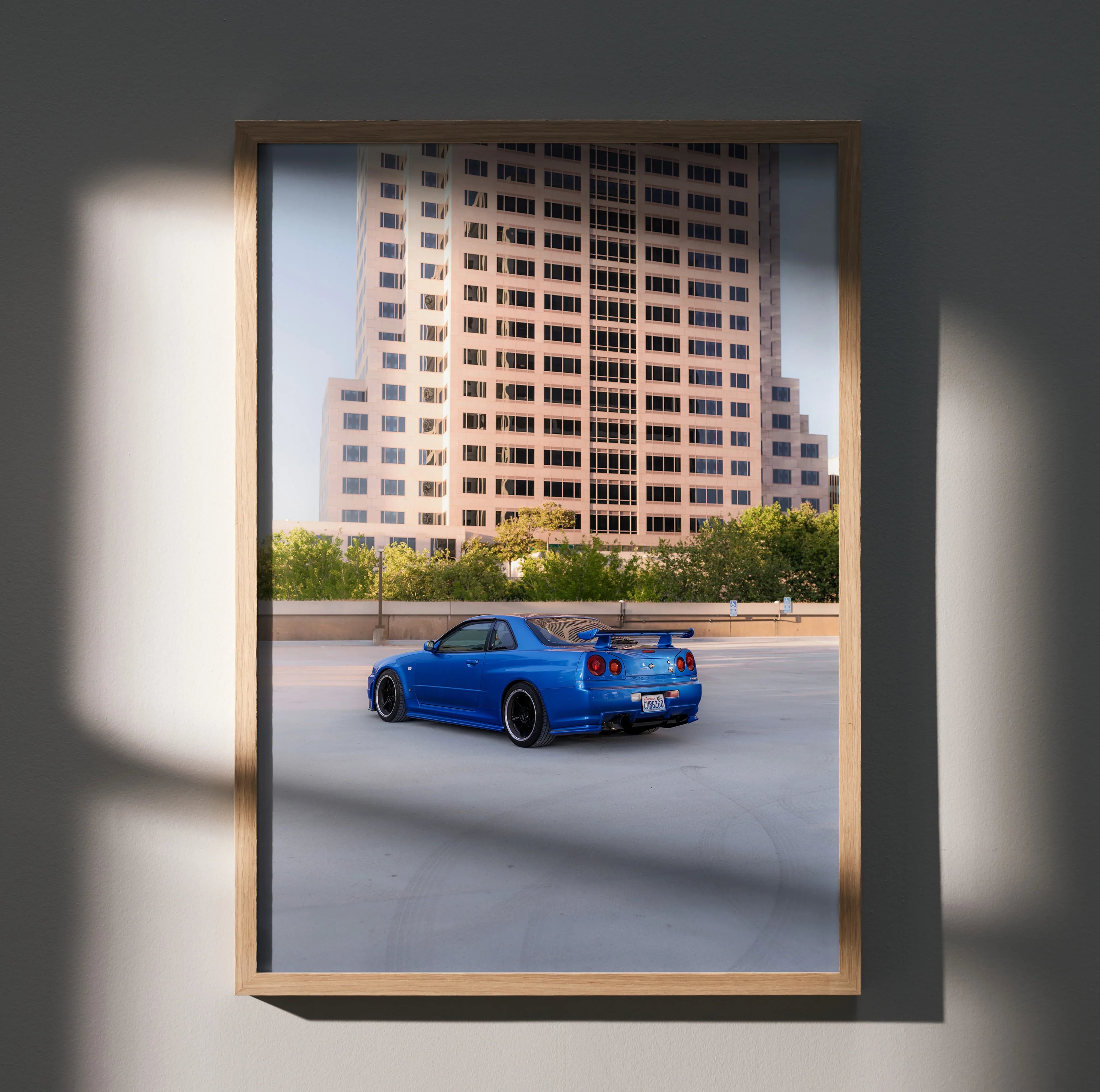 Blue Nissan R34 GTR Skyline poster wall art with urban skyline background in wooden frame.