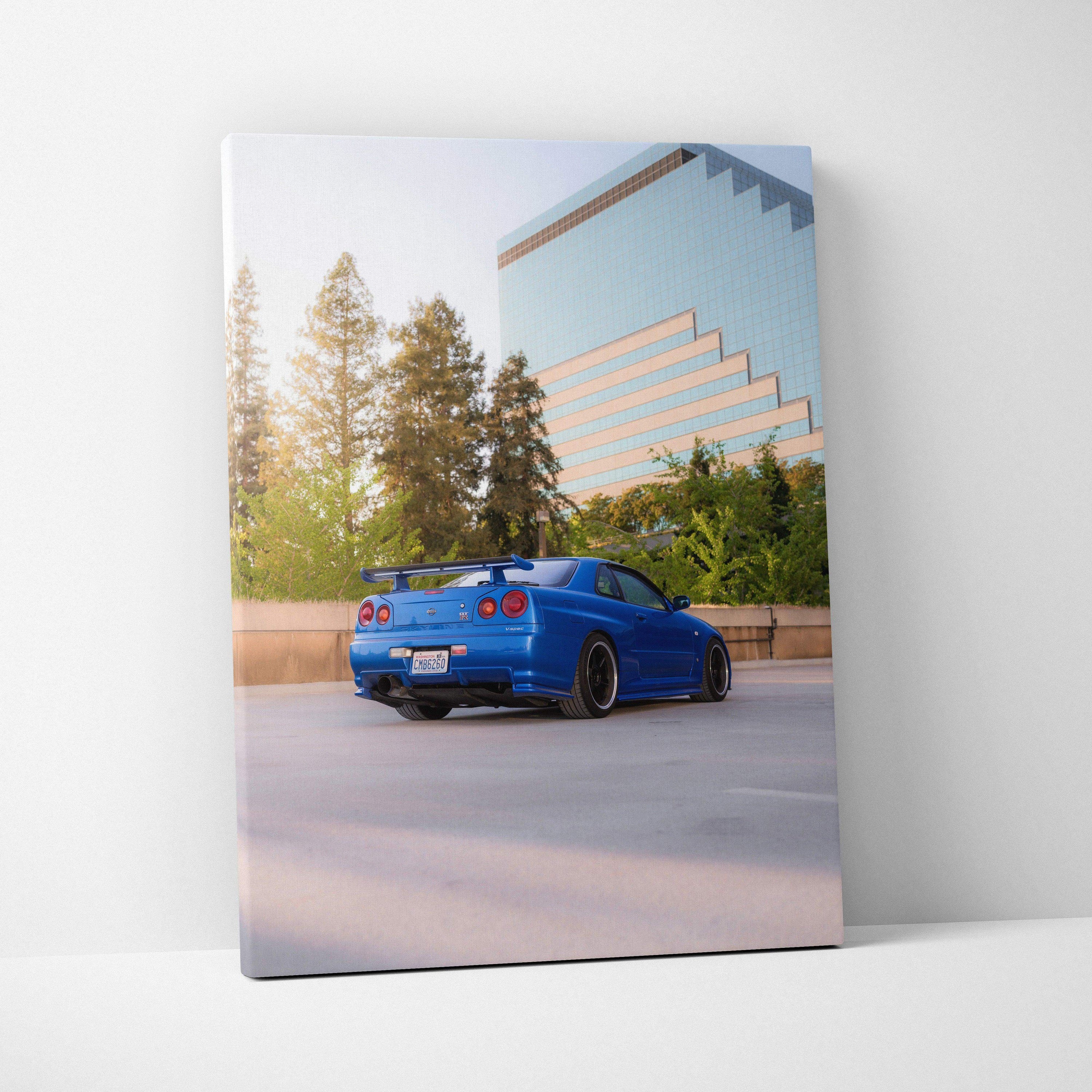 Blue Nissan GTR R34 Skyline parked by modern building on vertical canvas wall art.
