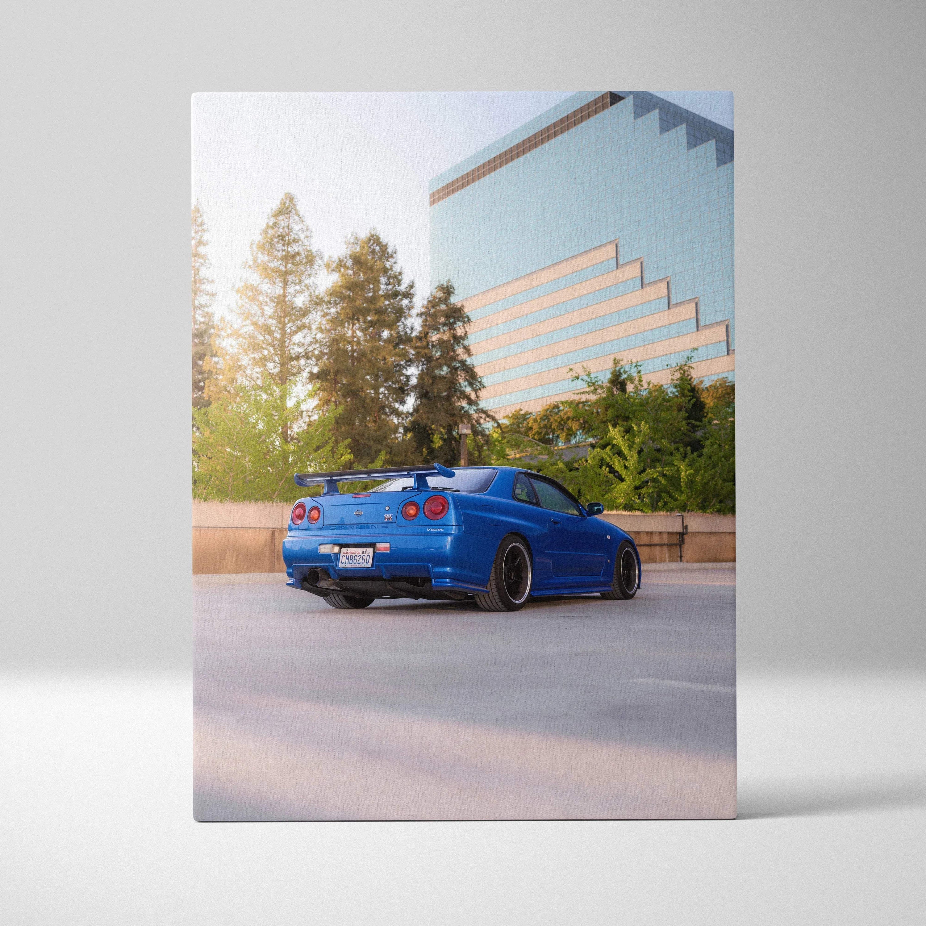 Blue Nissan R34 GTR parked with modern building and trees in background vertical canvas wall art.