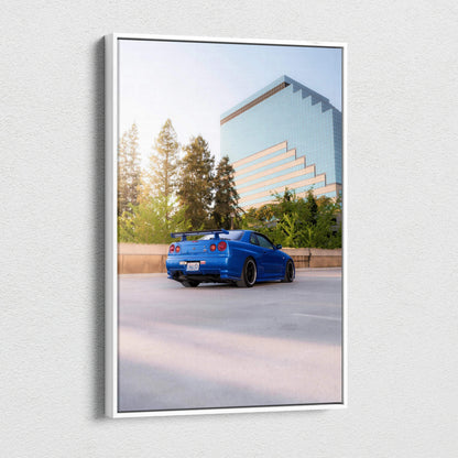 Vertical canvas art featuring a blue Nissan R34 GTR Skyline parked near a modern glass building and trees.