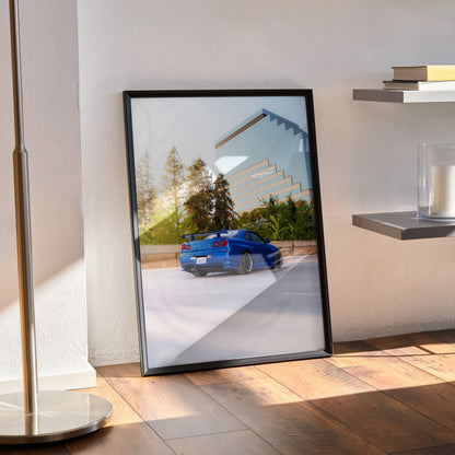 Nissan R34 GTR Skyline poster in black frame leaning on wall, vibrant car and forest background wall art.