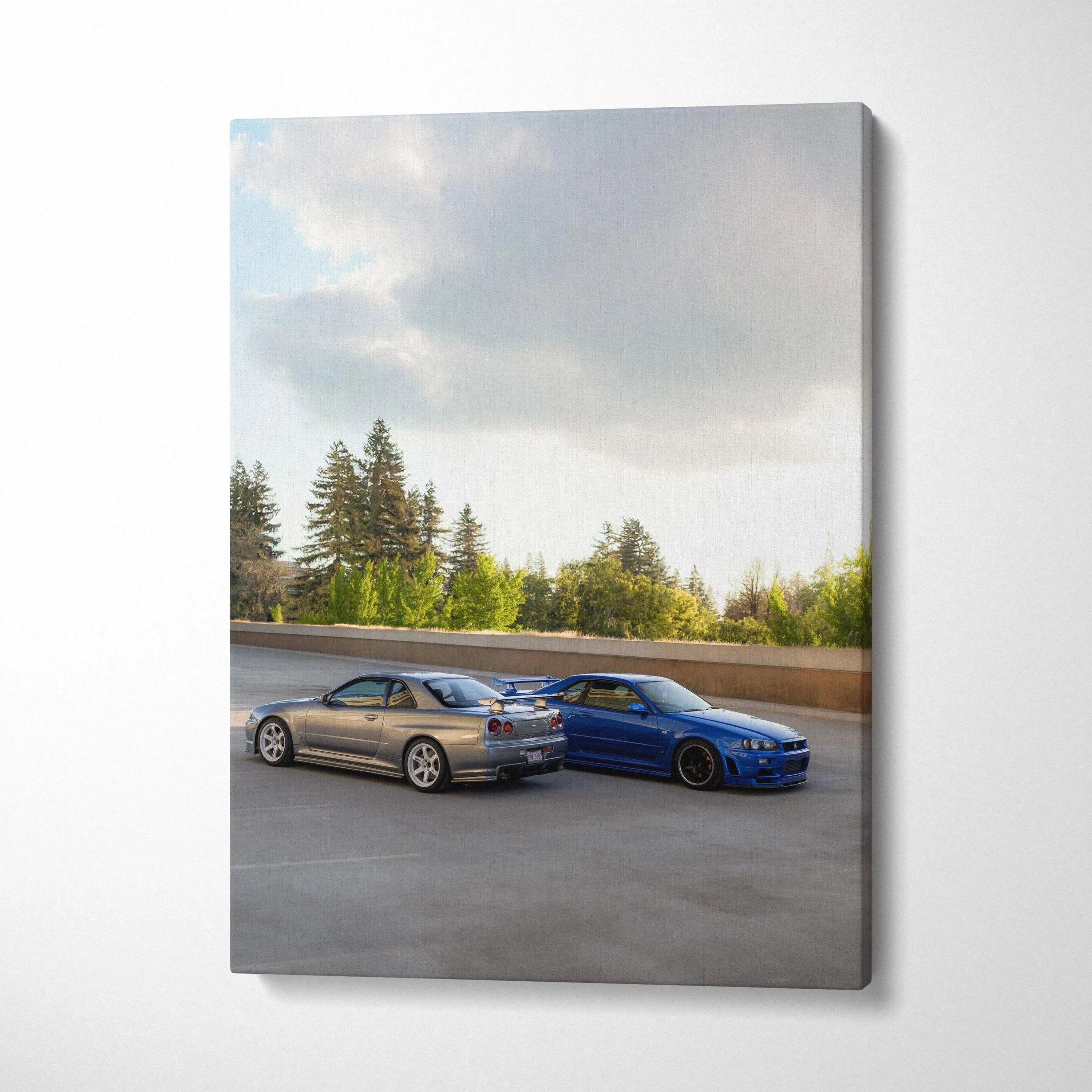 Vertical canvas art featuring Nissan R34 GTRs in silver and blue parked on open road under cloudy sky.
