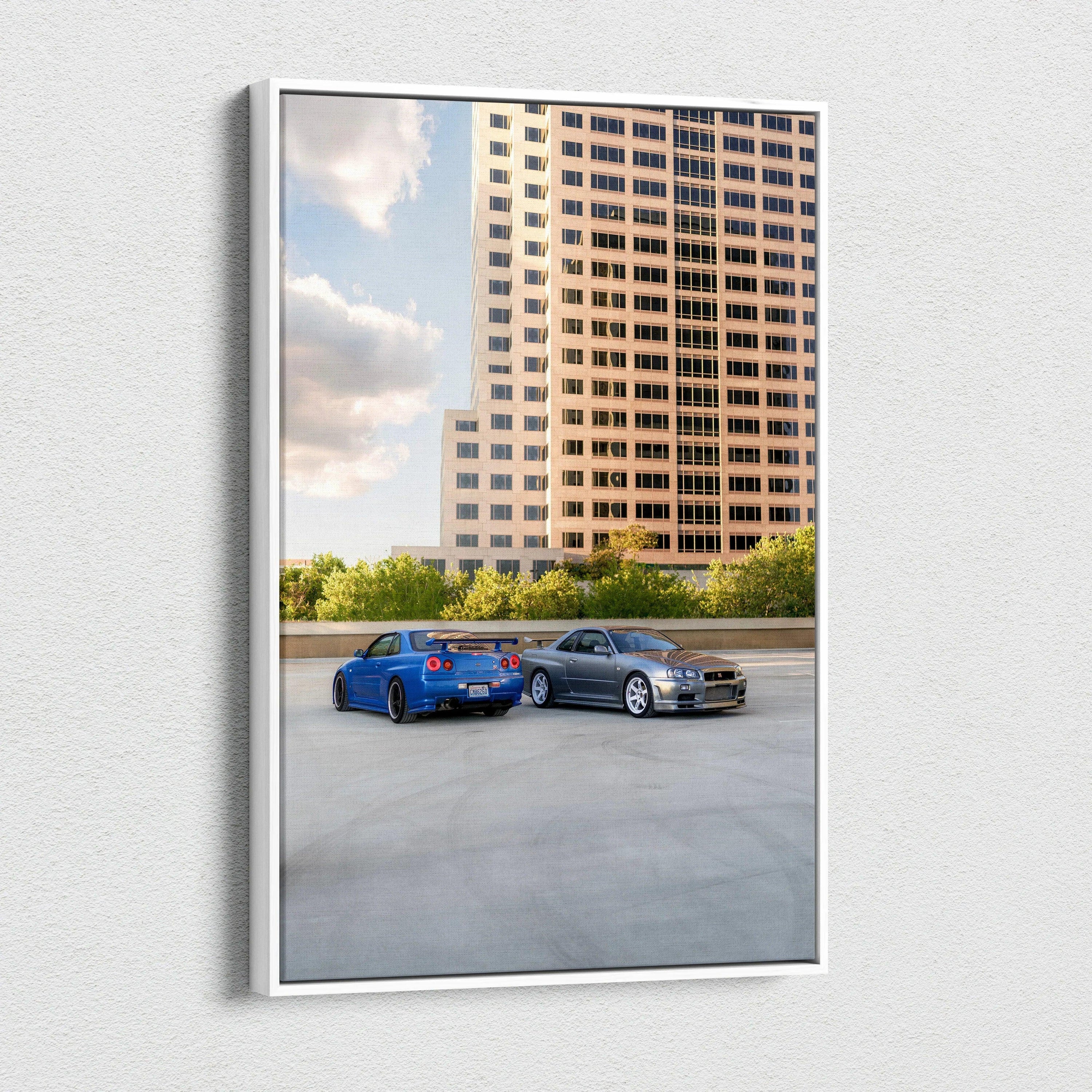 Vertical canvas wall art featuring blue Nissan R34 GTR and silver car parked by tall urban building.