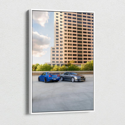 Vertical canvas wall art featuring blue Nissan R34 GTR and silver car parked by tall urban building.