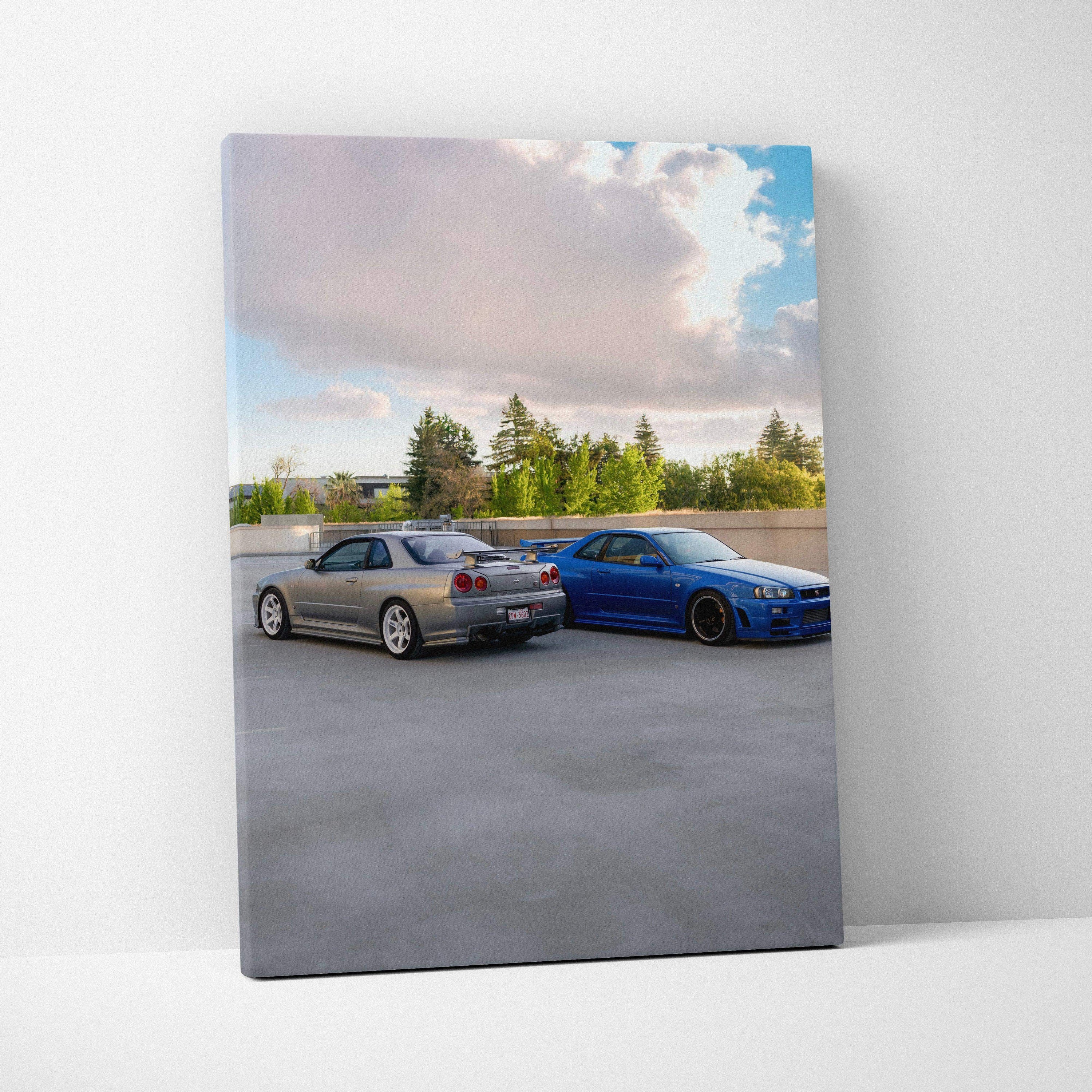 Vertical canvas wall art featuring silver and blue Nissan R34 GTR Skyline cars under a cloudy sky.