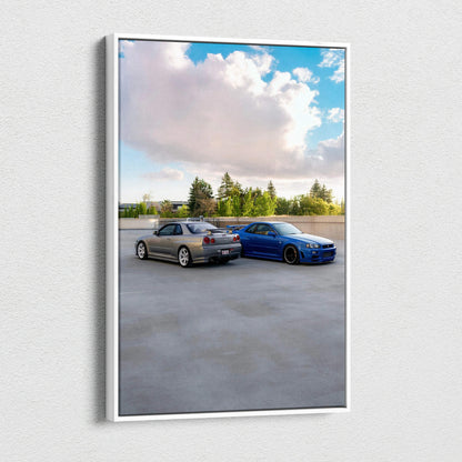 Canvas wall art featuring two Nissan GTR R34 Skyline cars parked on gray concrete under a blue sky with clouds.