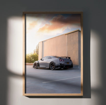 Nissan GTR R35 parked by concrete wall at sunset poster wall art with warm lighting.