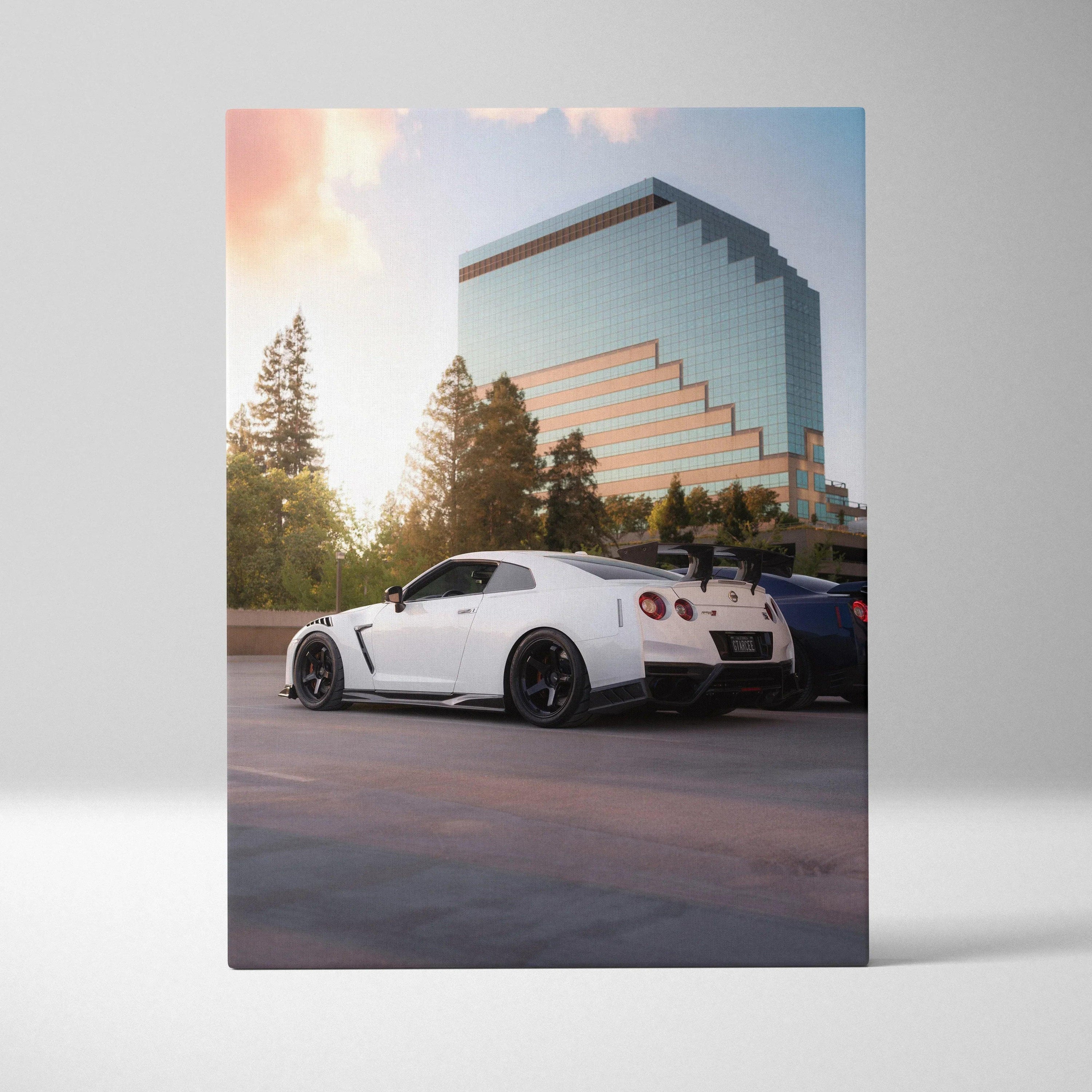 White Nissan GTR R35 parked at sunset with modern glass building backdrop, canvas wall art.