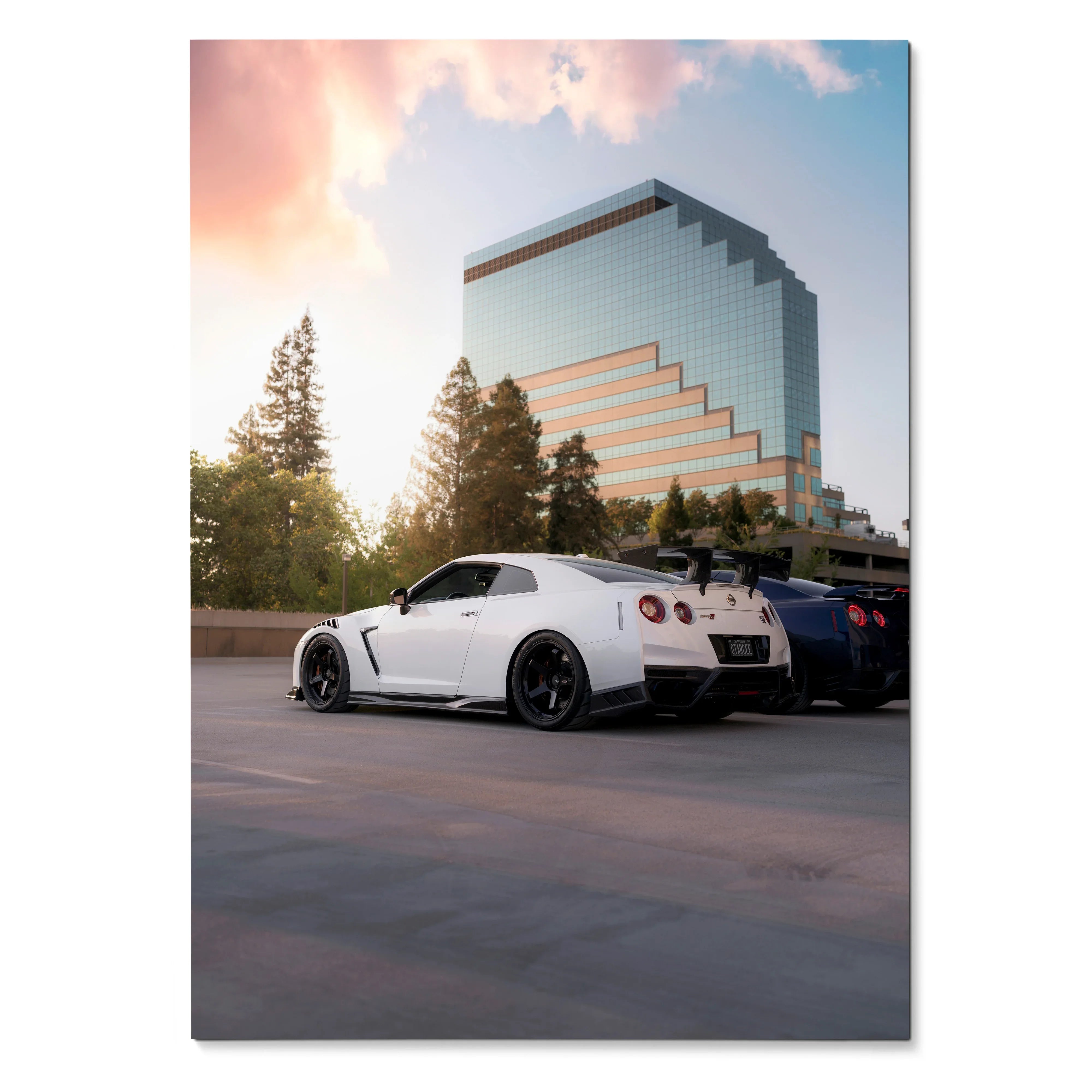 Nissan R35 GTR white sports car parked near modern glass building at sunset poster wall art.