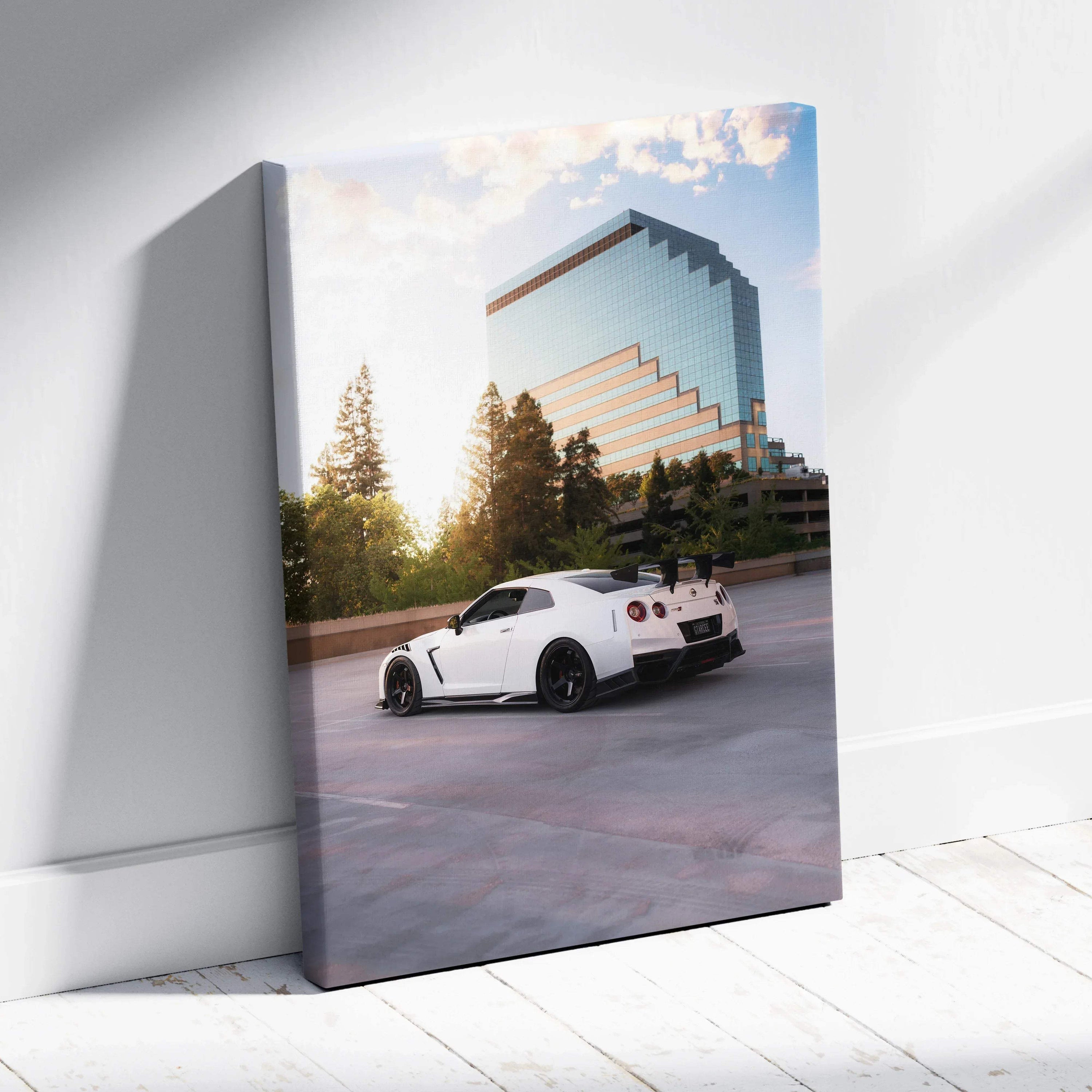 Vertical canvas art of white Nissan GTR R35 parked with reflective modern building and trees in background.
