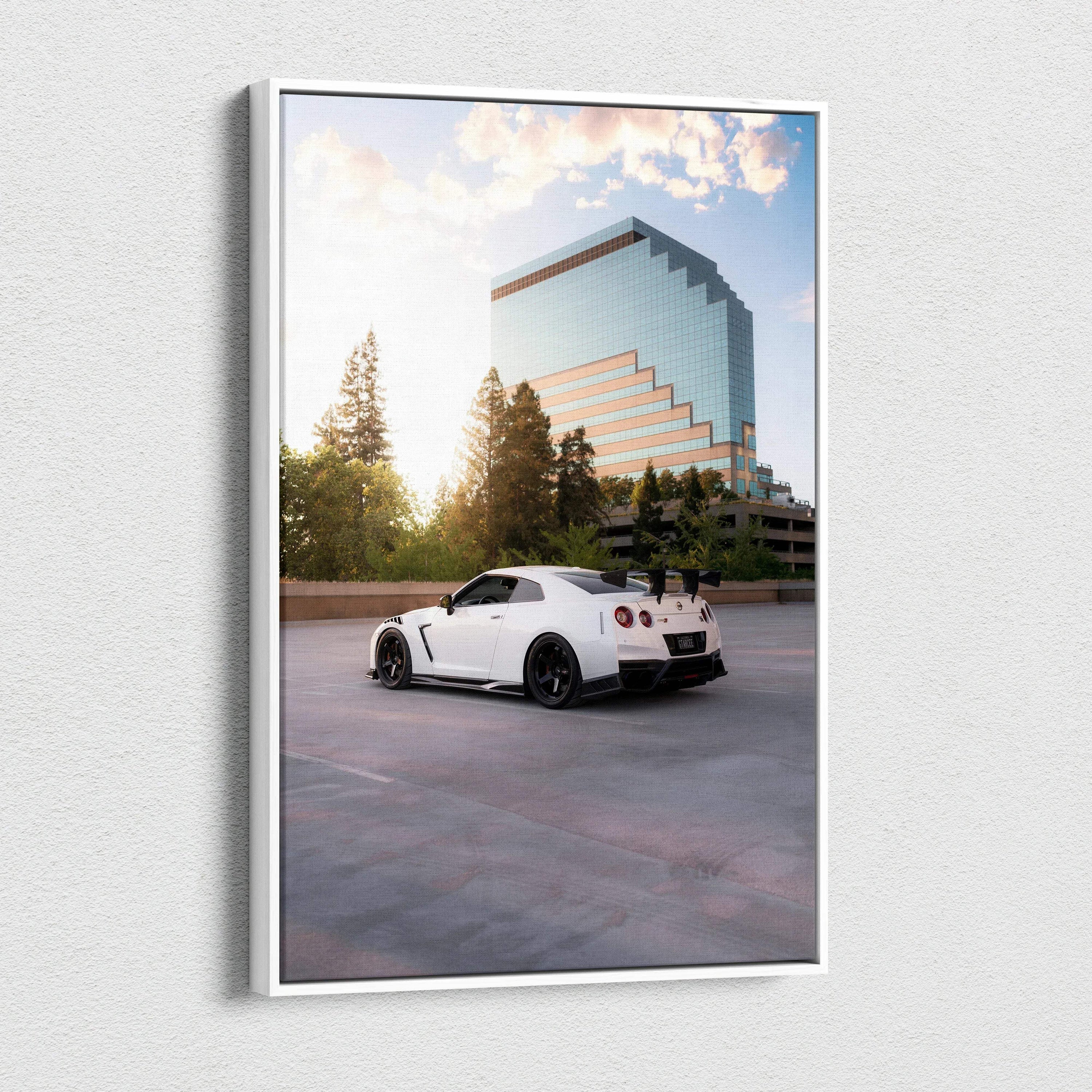 Vertical canvas wall art featuring a white Nissan GTR R35 parked by a modern glass building at sunset.