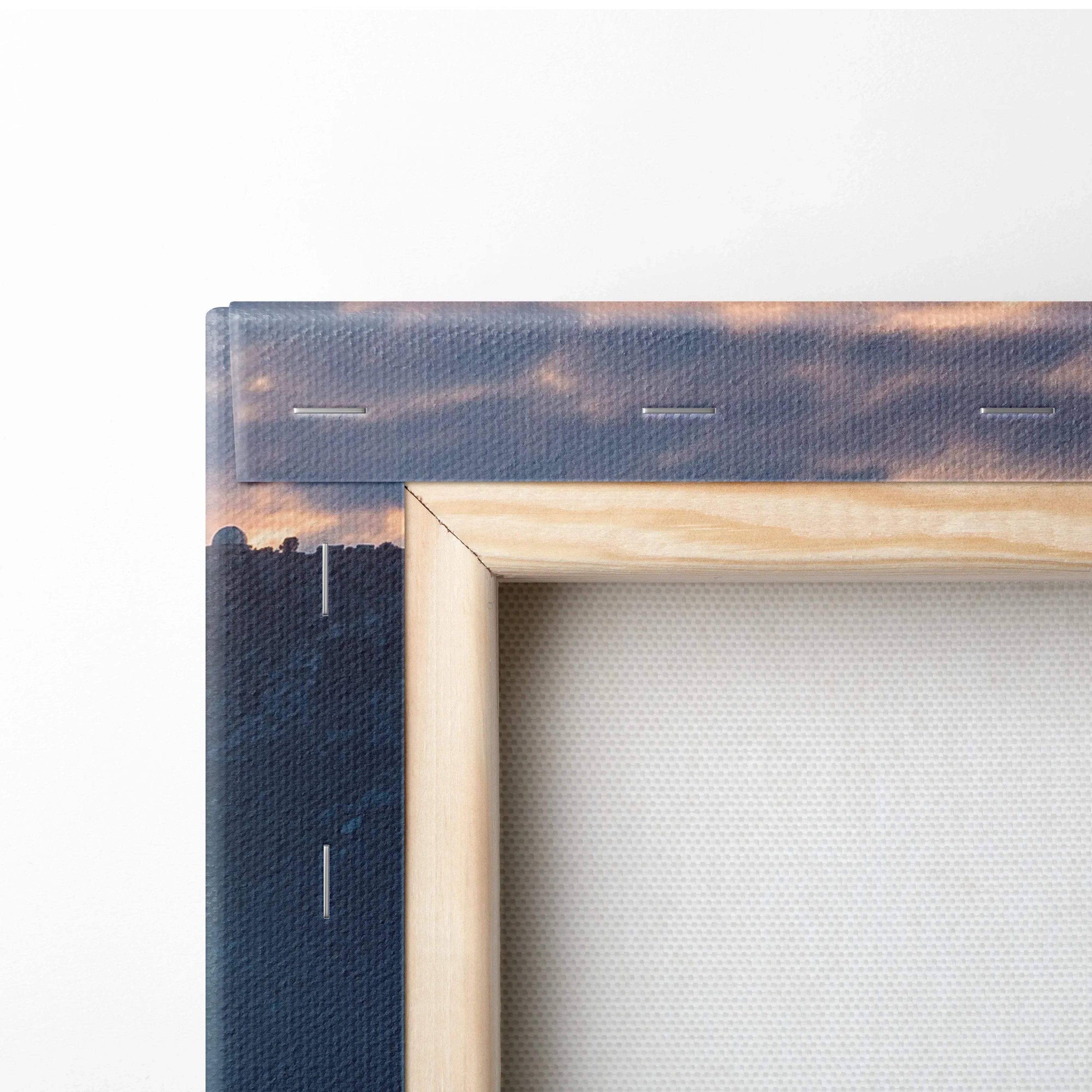 Close-up of wooden-framed canvas wall art with cityscape and cloudy sky print.