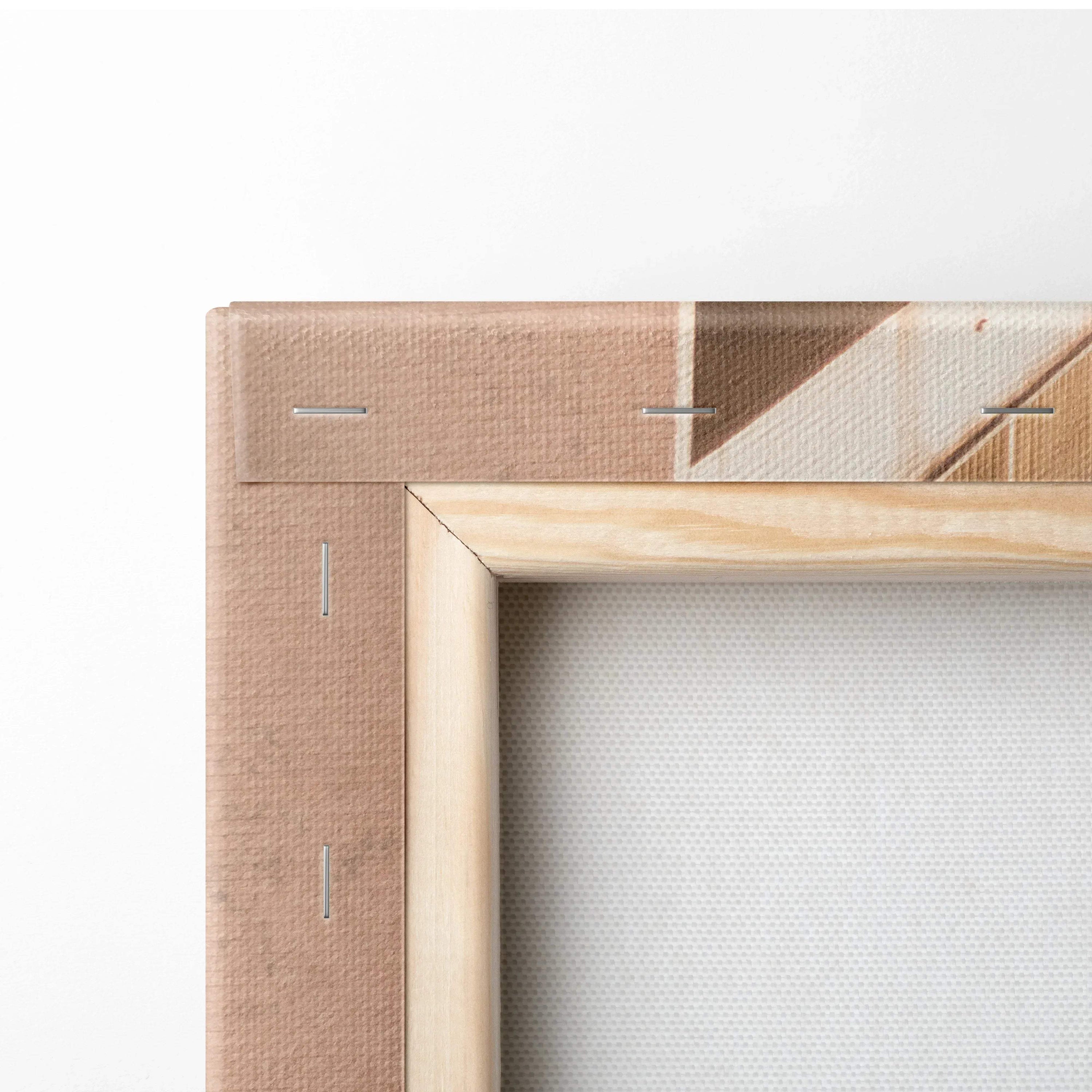 Close-up of beige fabric canvas stretched on a light natural wood frame with visible staples and folded corners.