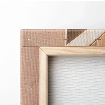 Close-up of beige fabric canvas stretched on a light natural wood frame with visible staples and folded corners.