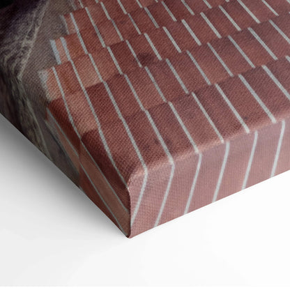 Close-up of canvas wall art showing textured print of red brick building facade with white vertical accents and shadows.