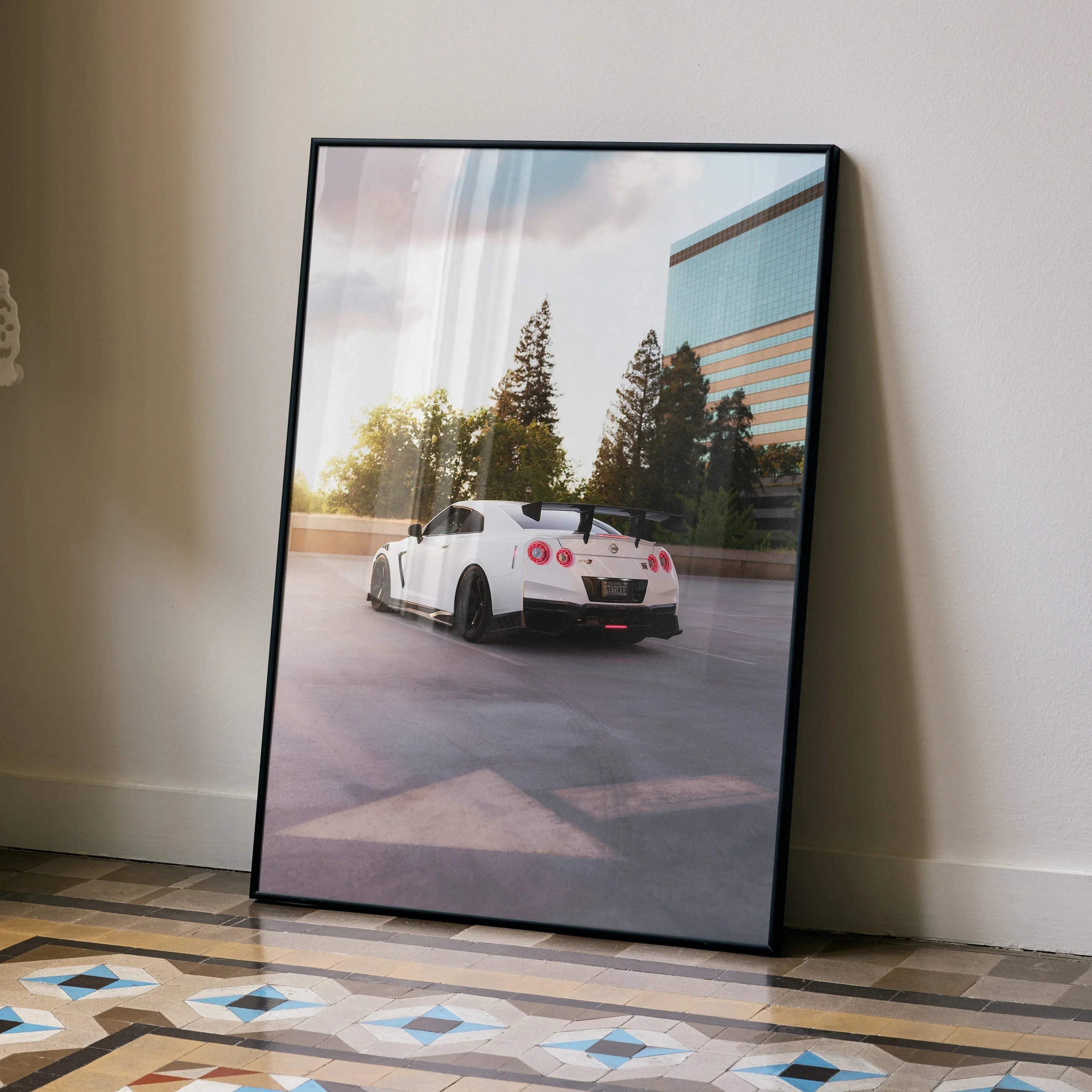 Nissan GTR R35 poster wall art with white sports car parked near trees and glass building at sunset.