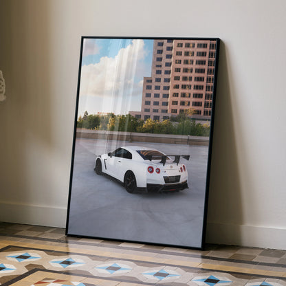 Nissan GTR R35 white sports car driving near modern building poster wall art in black frame.