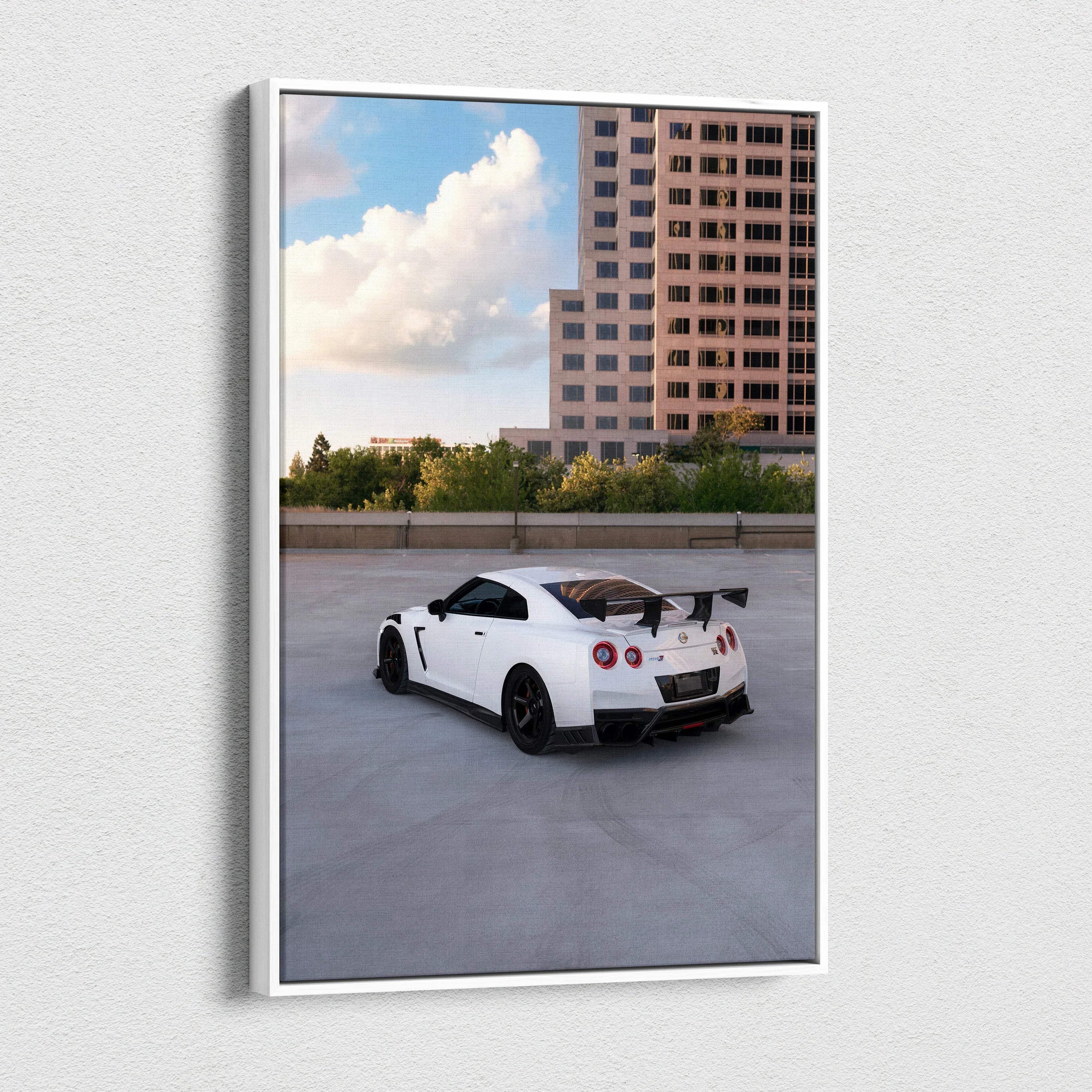 Vertical canvas wall art featuring a white Nissan R35 GTR against an urban backdrop with a tall building and blue sky.