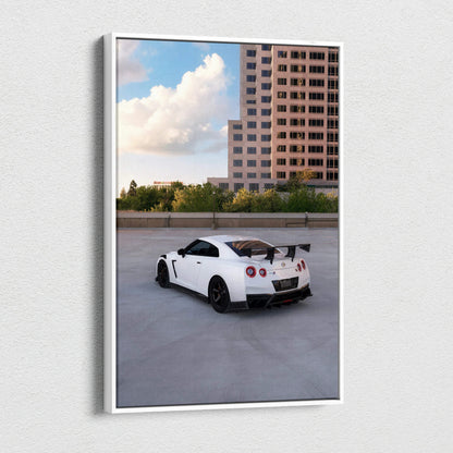 Vertical canvas wall art featuring a white Nissan R35 GTR against an urban backdrop with a tall building and blue sky.