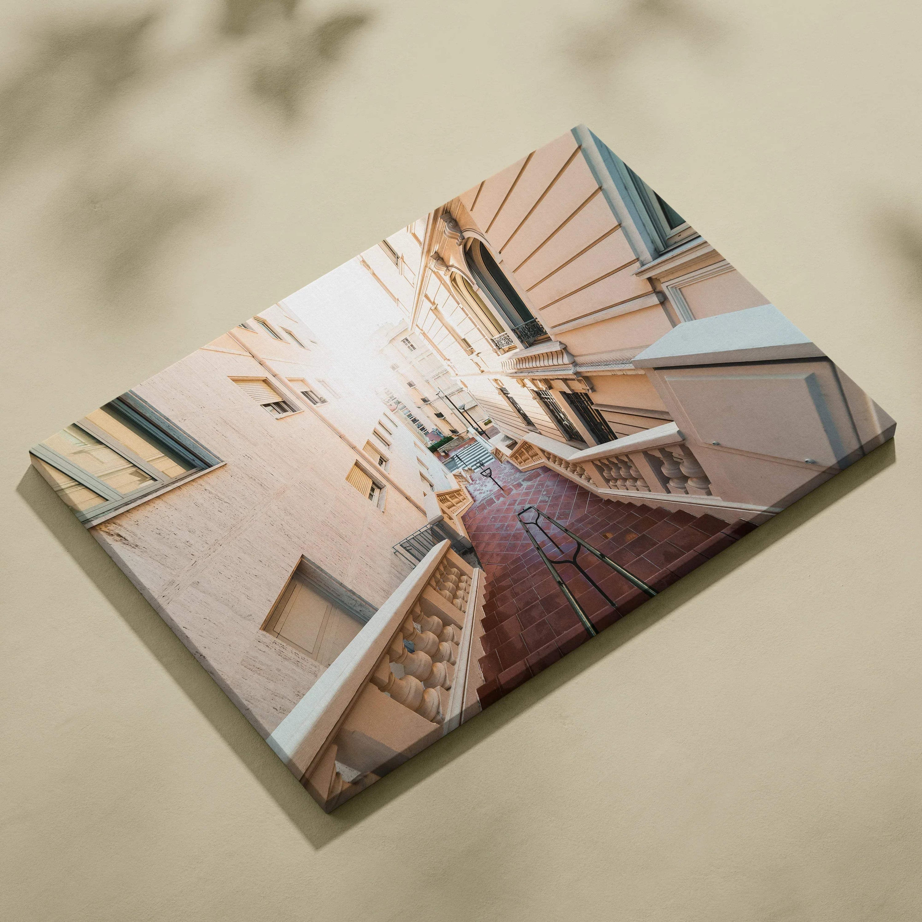 Rectangular canvas wall art featuring upward view of beige and white buildings with narrow red brick pathway and blue.