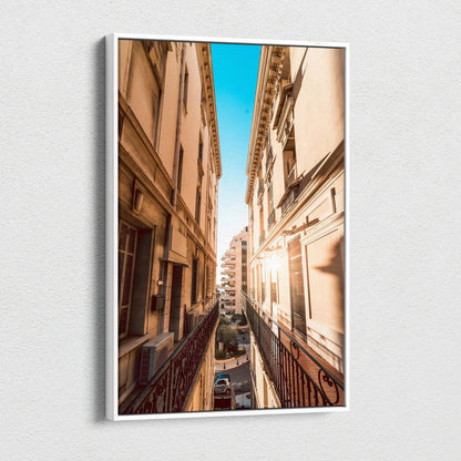 Narrow urban street view between tall beige buildings under bright blue sky on vertical canvas wall art.